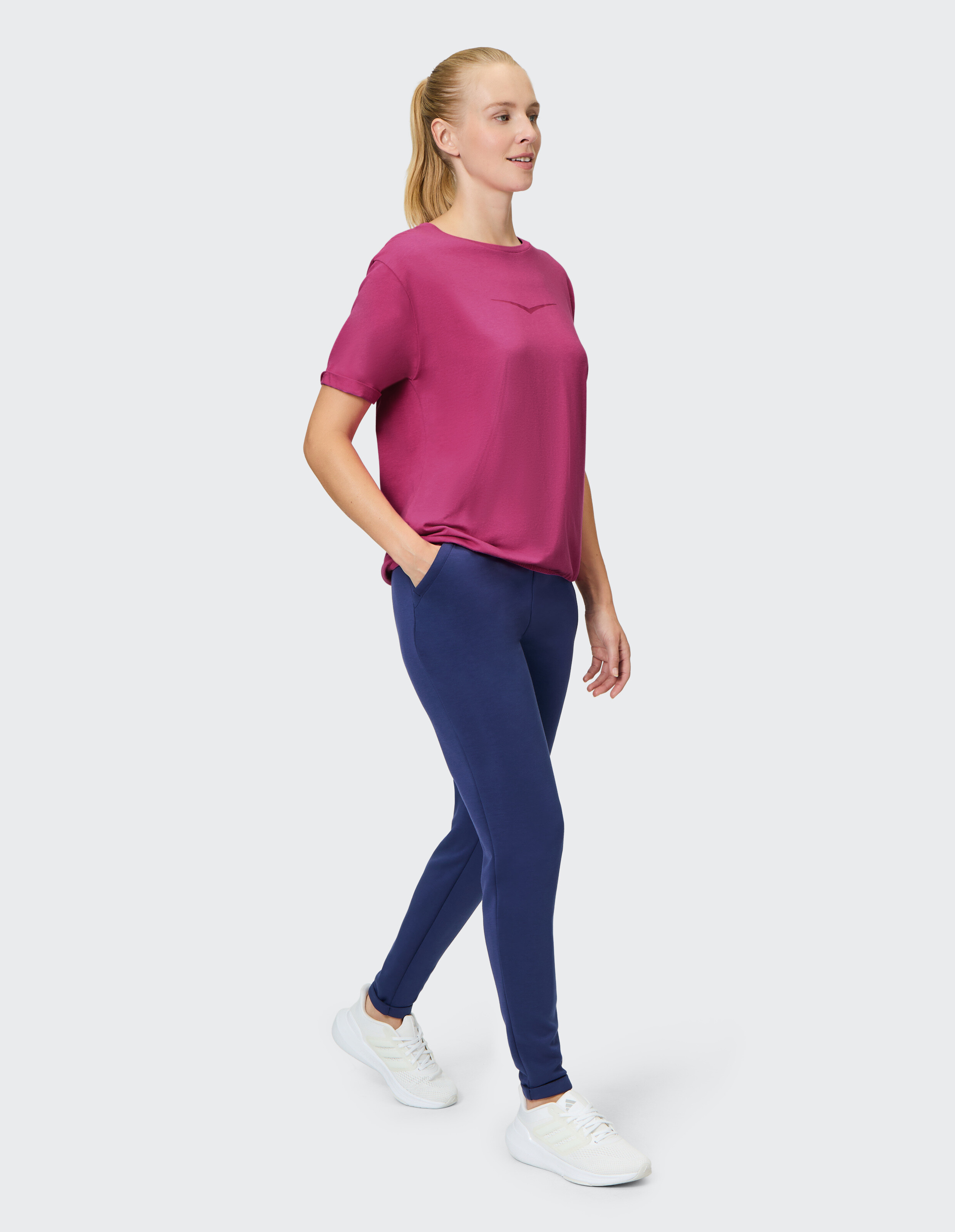 Frau trägt ein magentafarbenes T-Shirt und dunkelblaue Freizeithosen für einen bequemen, stilvollen Look.