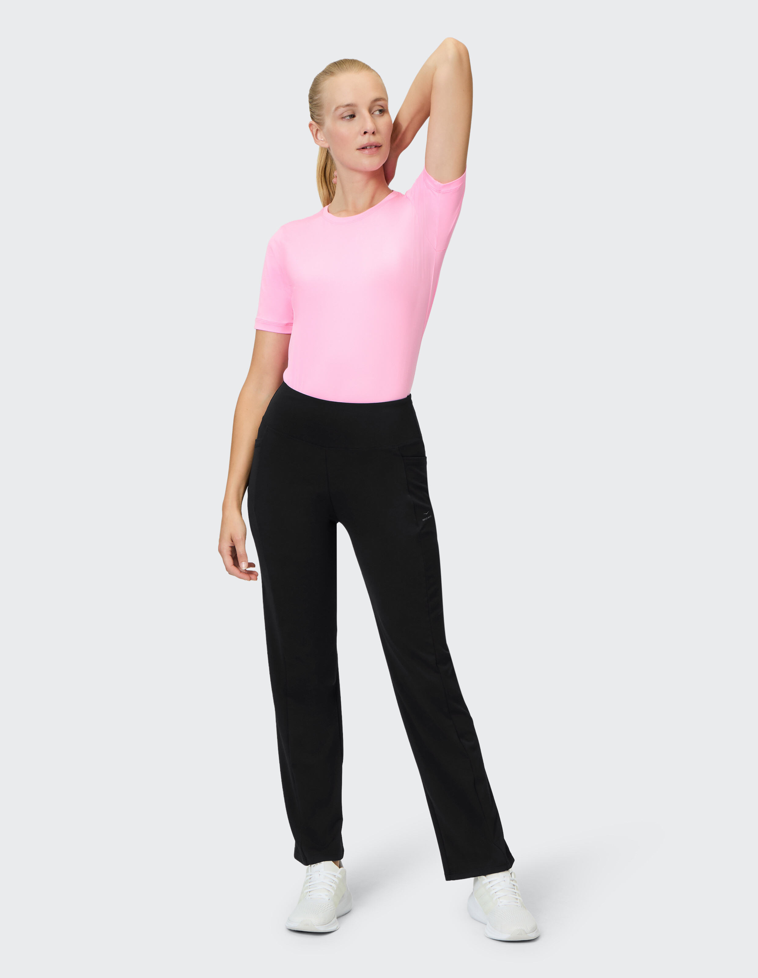 Frau trägt ein rosa T-Shirt und eine schwarze Freizeithose für einen bequemen, stilvollen Look.