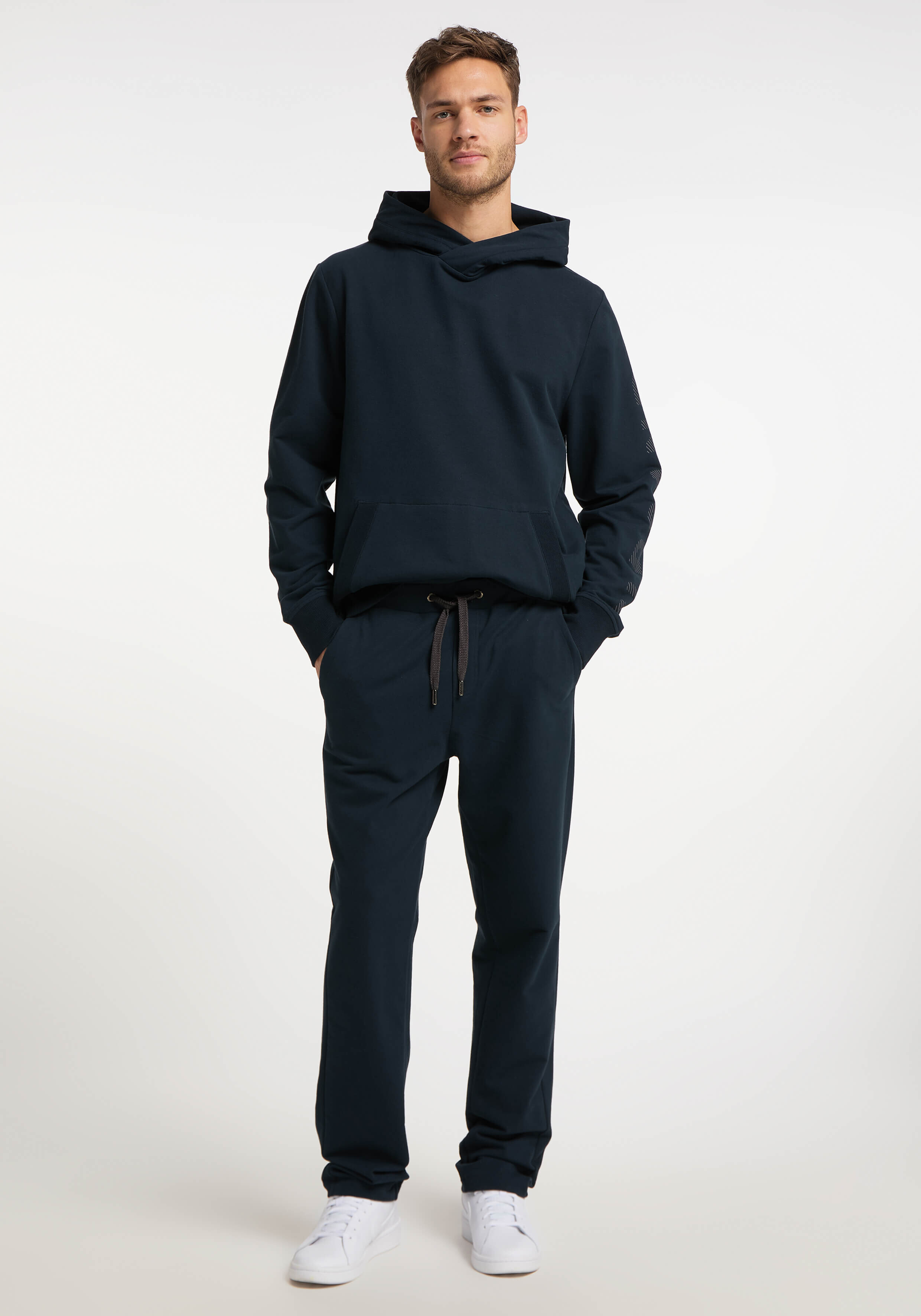 Mann trägt einen dunkelblauen Kapuzenpullover und eine passende Jogginghose für einen gemütlichen, lässigen Look.