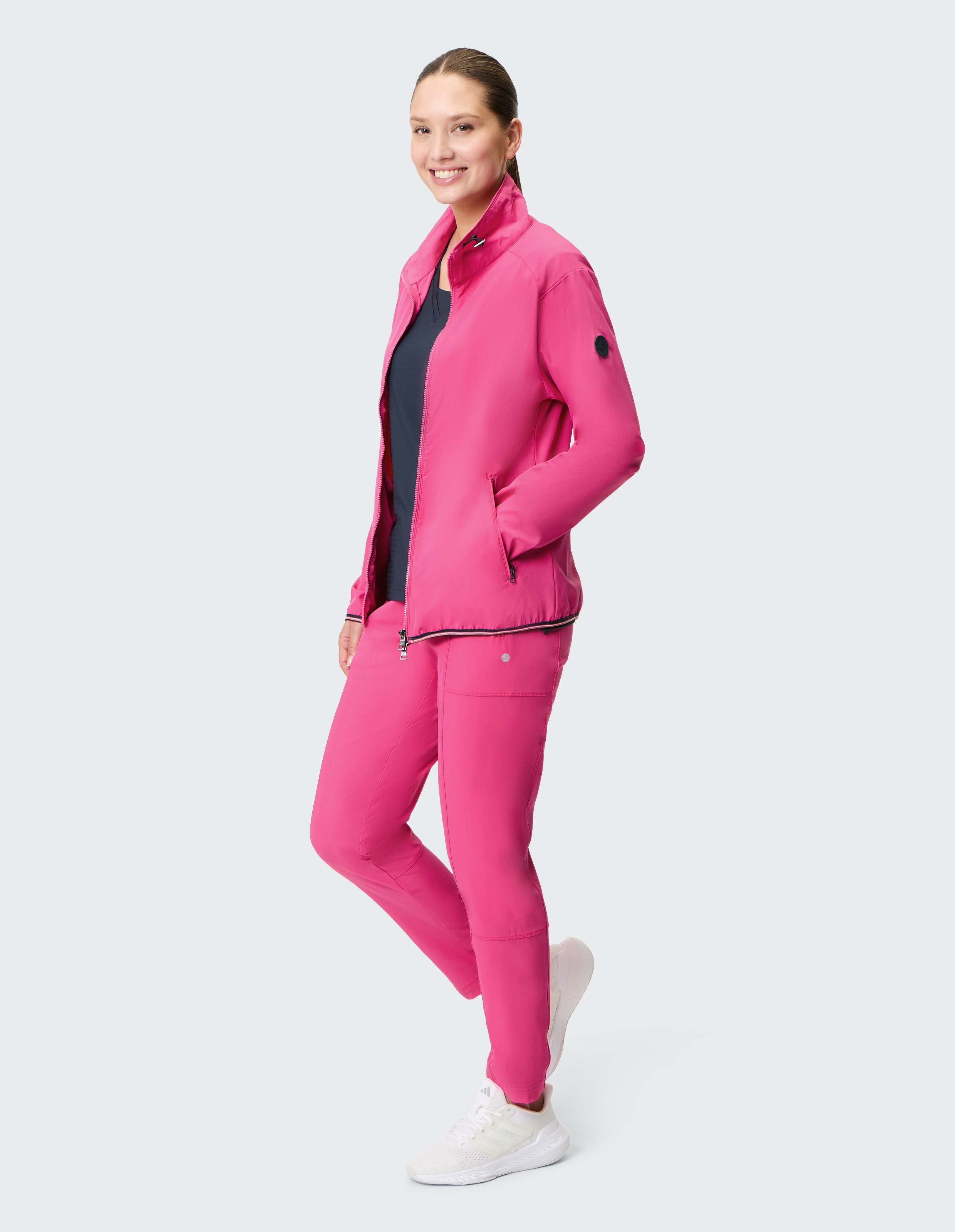 Frau trägt eine rosa Jacke mit Reißverschluss und passende Freizeithosen für einen bequemen Look.