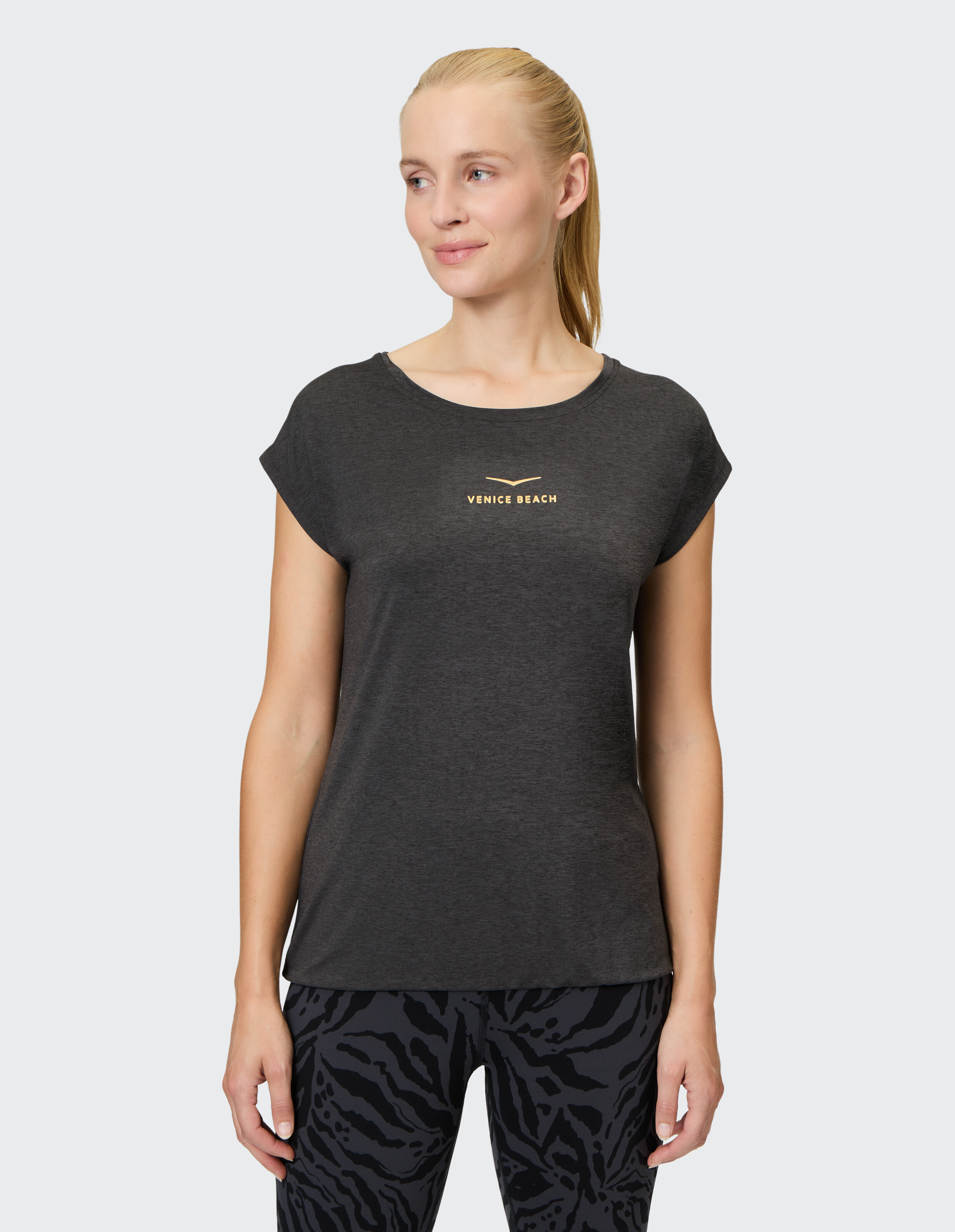 Frau trägt ein dunkelgraues Venice Beach-T-Shirt mit Flügelärmeln für lässigen Komfort.