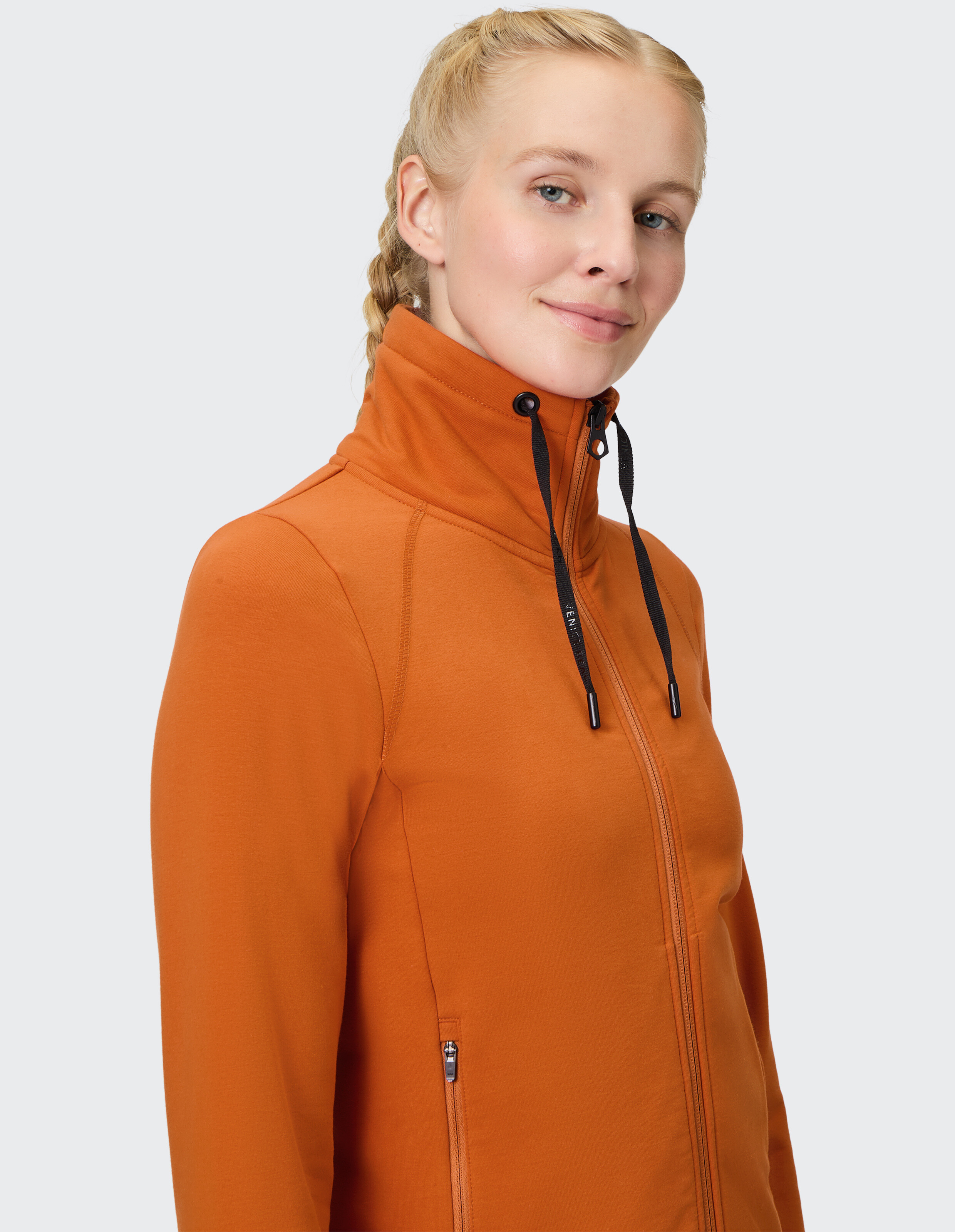 Frau trägt eine gemütliche orangefarbene Sweatjacke von Venice Beach Florence mit hohem Kragen.