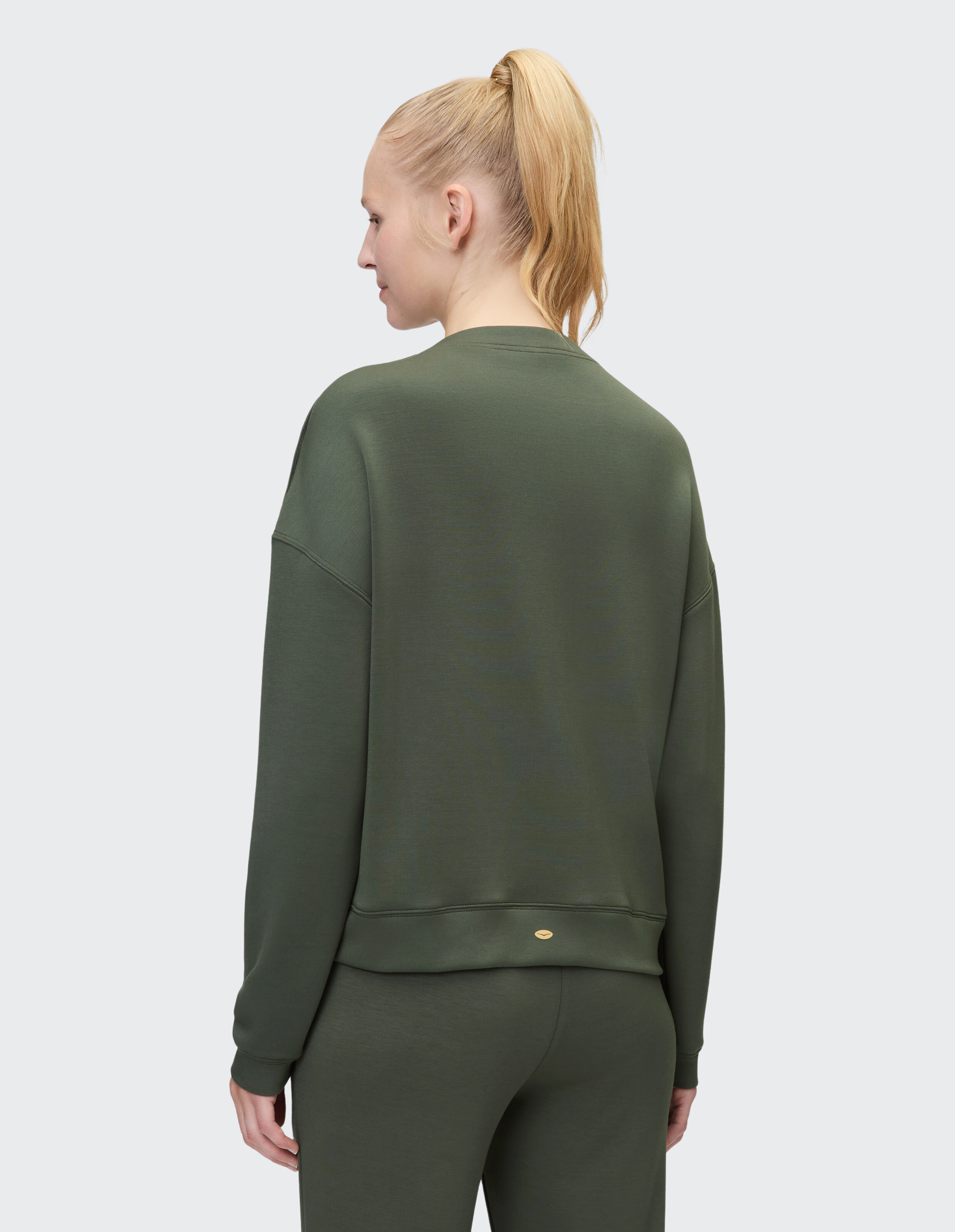 Frau trägt ein gemütliches olivgrünes Venice Beach Cody-Sweatshirt, Rückansicht.