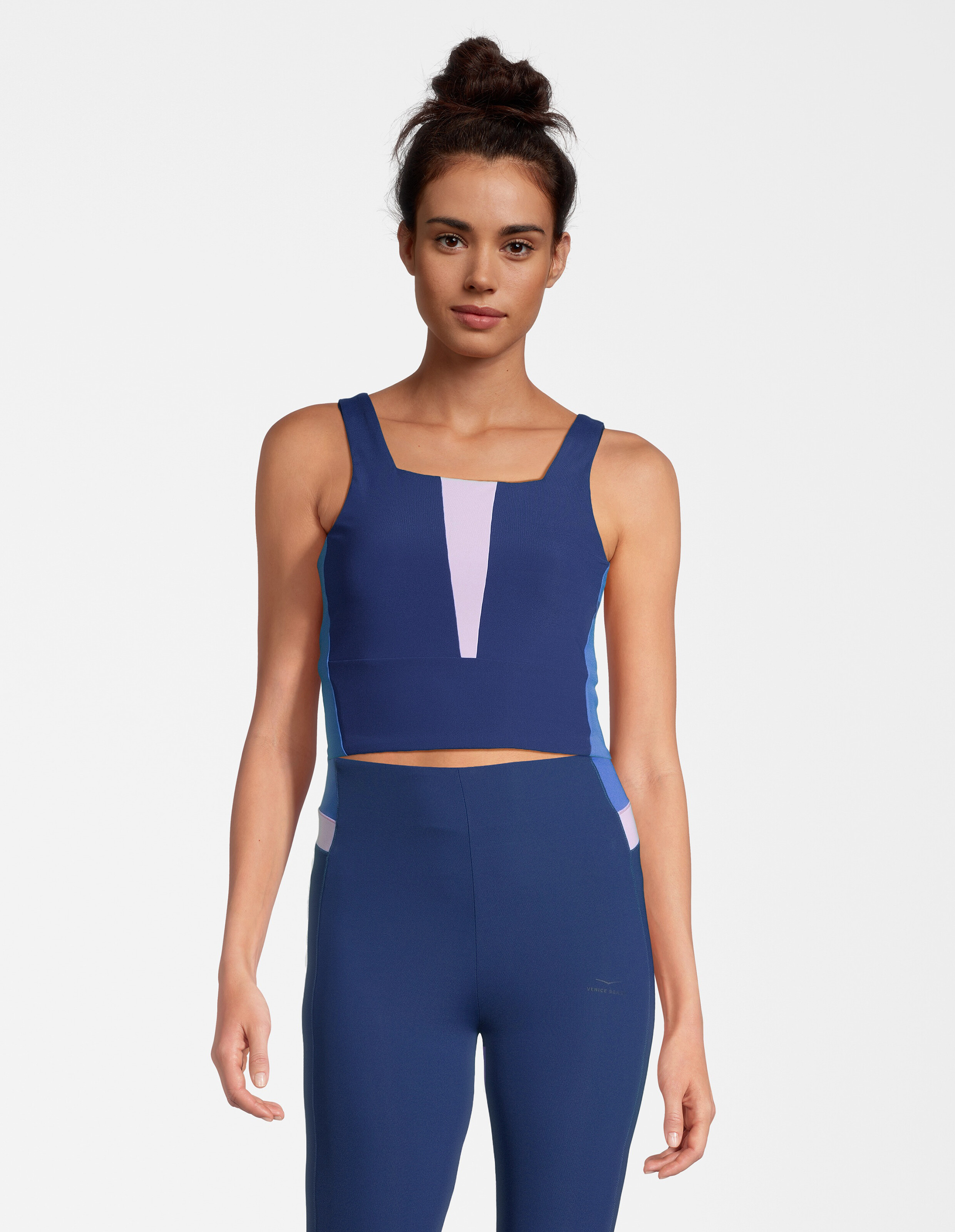 Frau trägt ein blaues und lilafarbenes Crop-Top in Blockfarben für einen lässigen, sportlichen Stil.