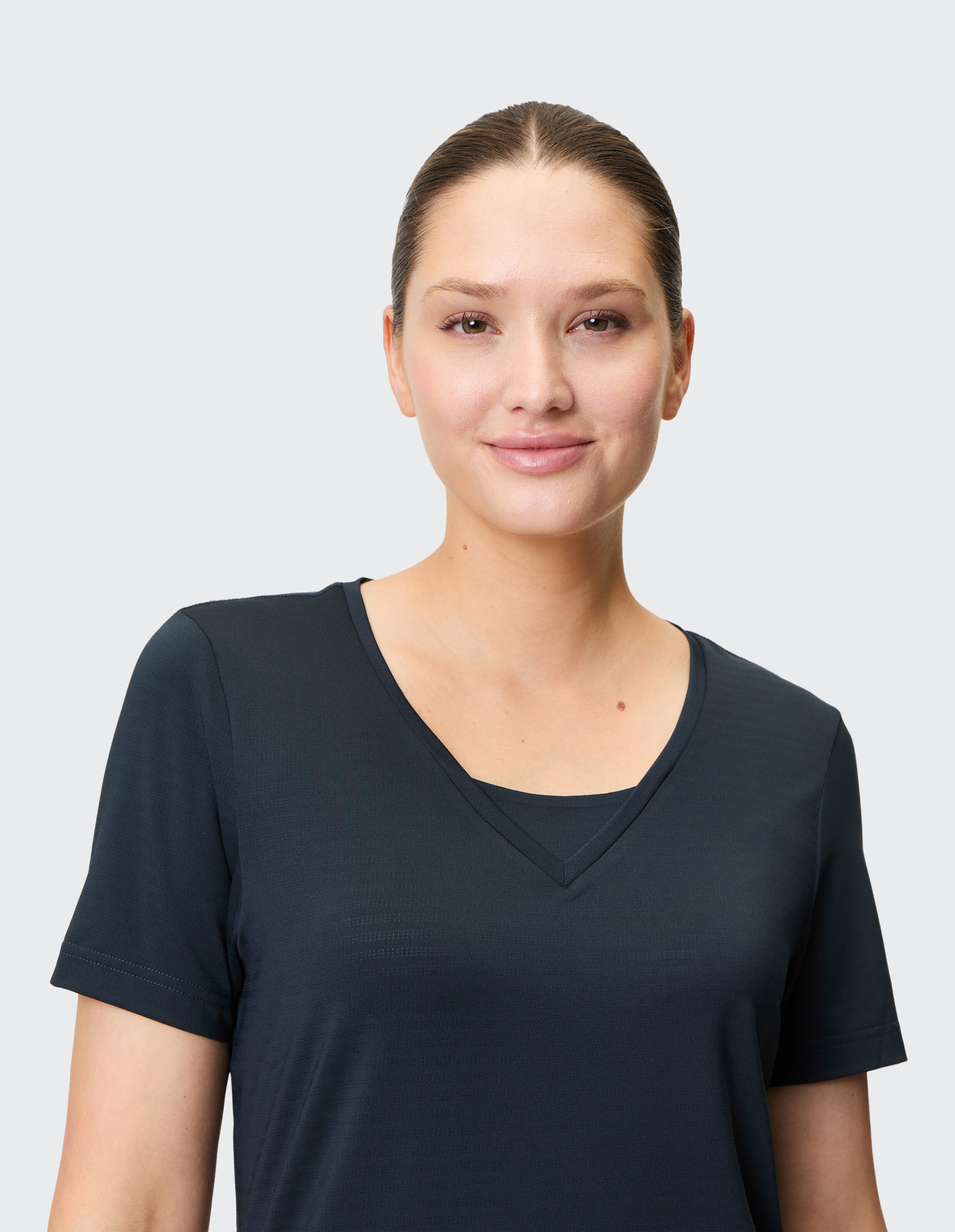 Nahaufnahme einer Frau in einem dunkelblauen T-Shirt mit V-Ausschnitt, die einen lässigen Stil unterstreicht.