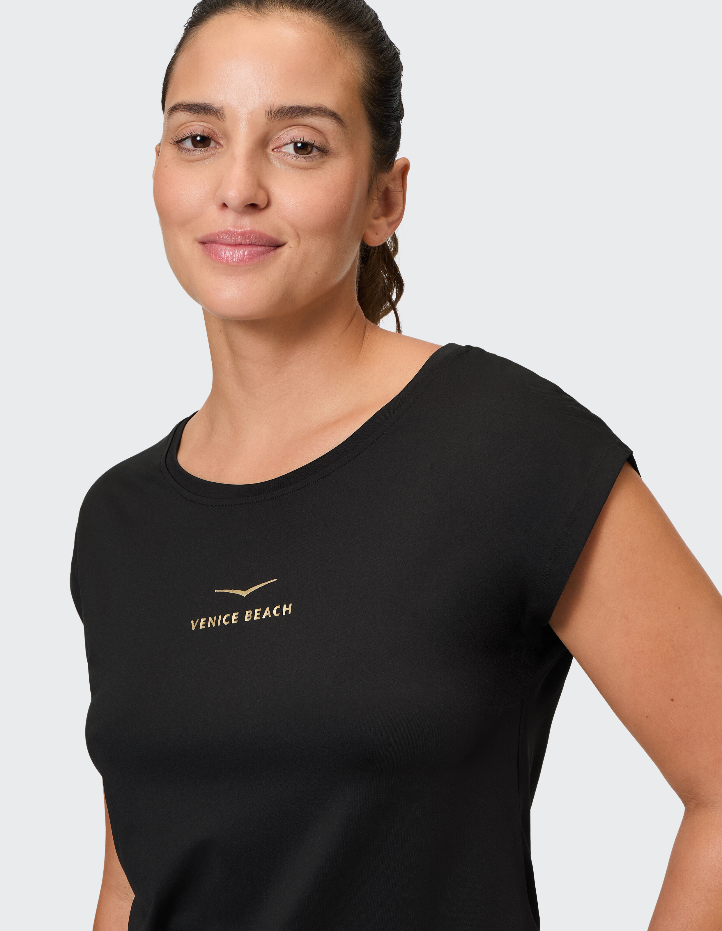 Nahaufnahme einer Frau in einem schwarzen T-Shirt mit „Venice Beach“-Logo im lässigen Stil.