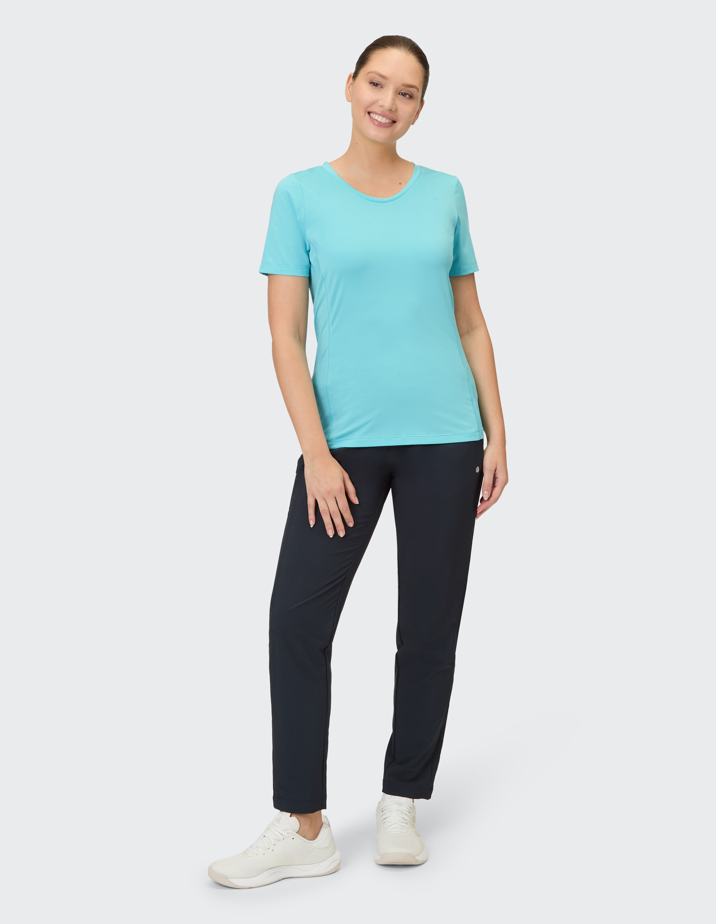 Ein lächelndes Model trägt ein himmelblaues kurzärmeliges Shirt und eine schwarze Sporthose.