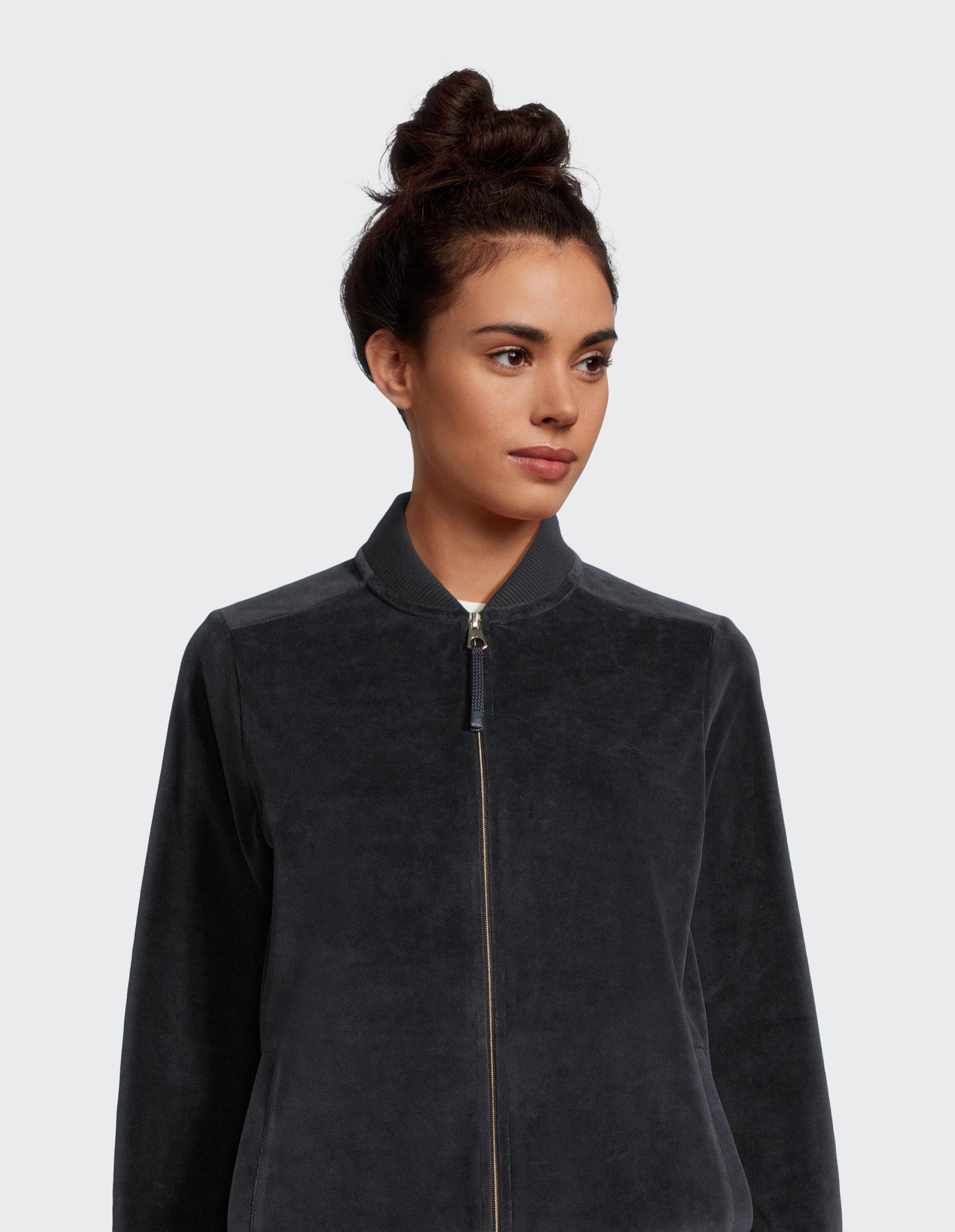 Frau trägt eine gemütliche dunkelgraue Velours-Bomberjacke für lässige Loungewear.