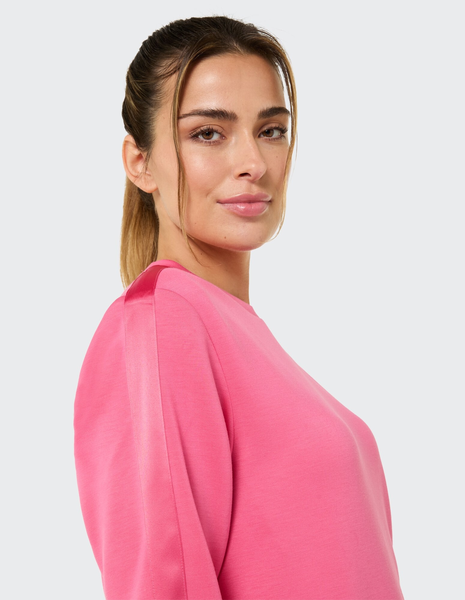 Nahaufnahme einer Frau in einem rosa Freizeit-Sweatshirt mit entspannter Passform.