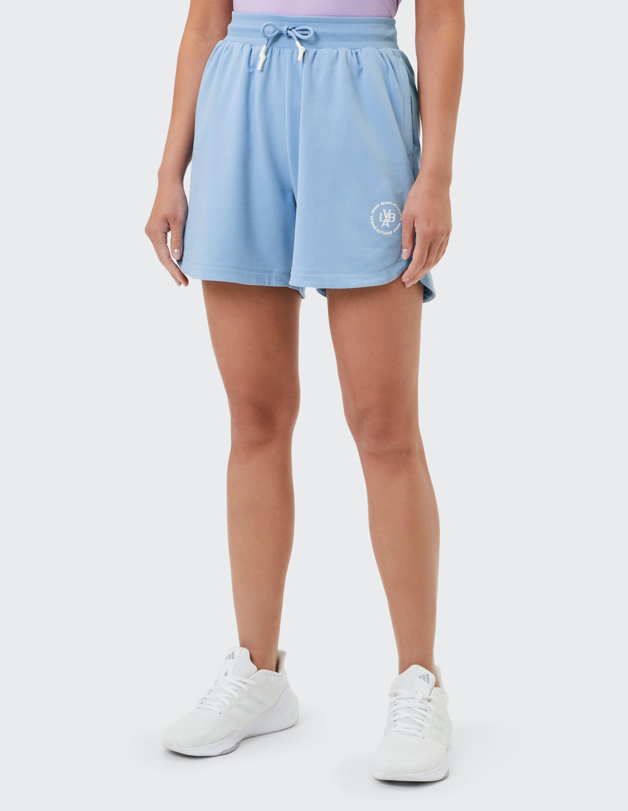 Hellblaue Freizeitshorts mit Kordelzug und Logo, gepaart mit weißen Sneakers.