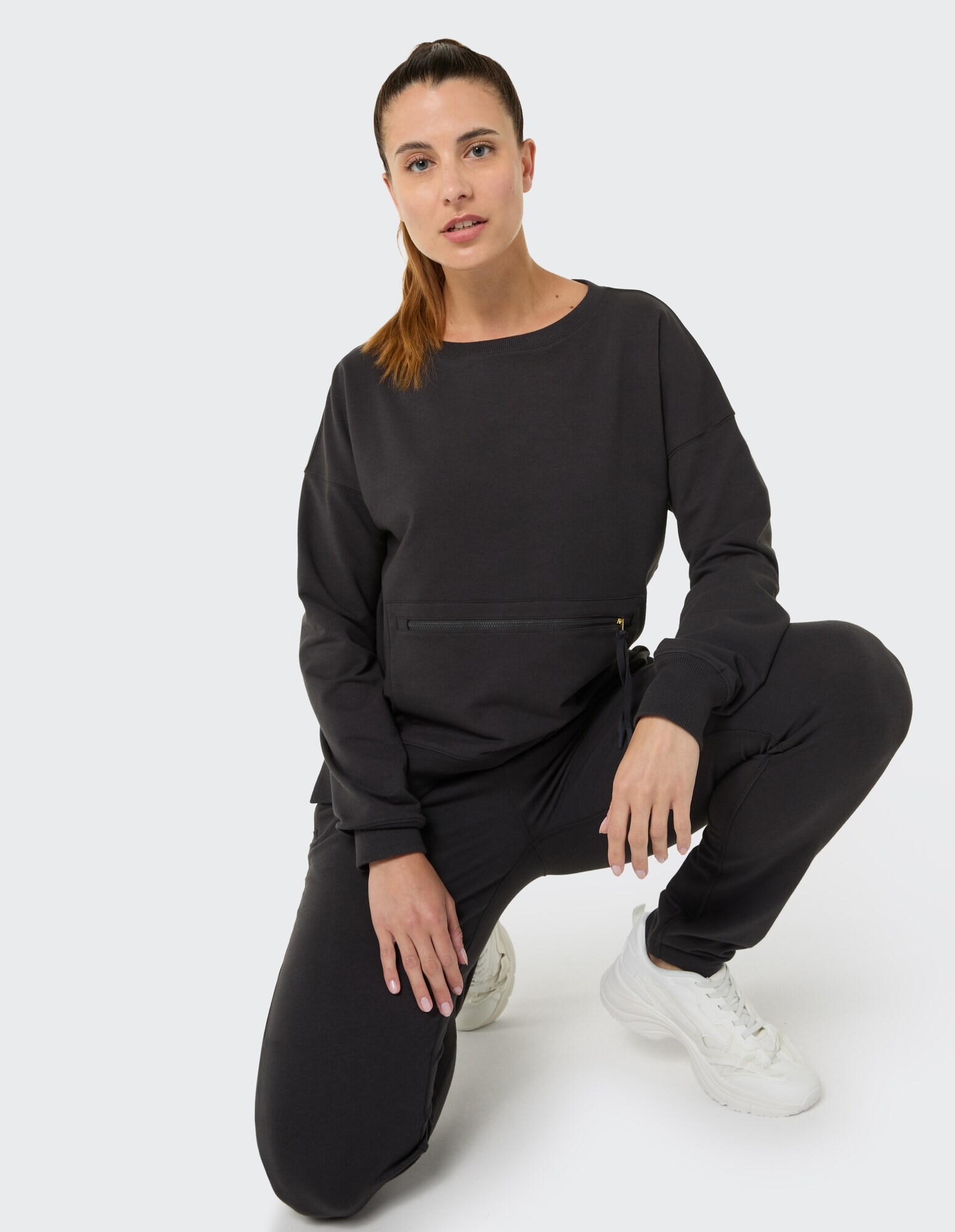 Frau in einem schwarzen Freizeitoutfit mit Reißverschlusstasche, perfekt zum Entspannen.