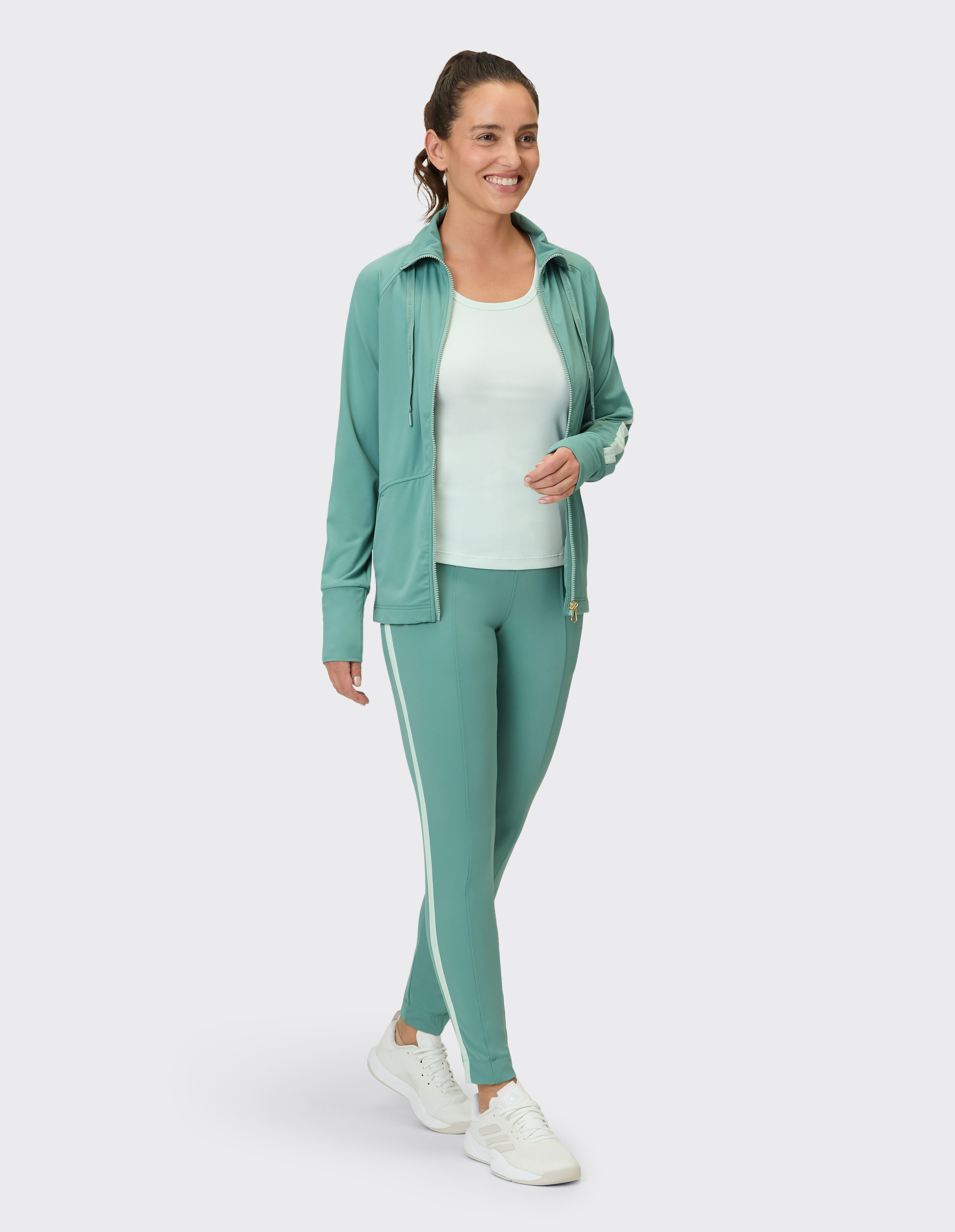 Frau in einem mintgrünen Athleisure-Set mit Reißverschlussjacke und Leggings.