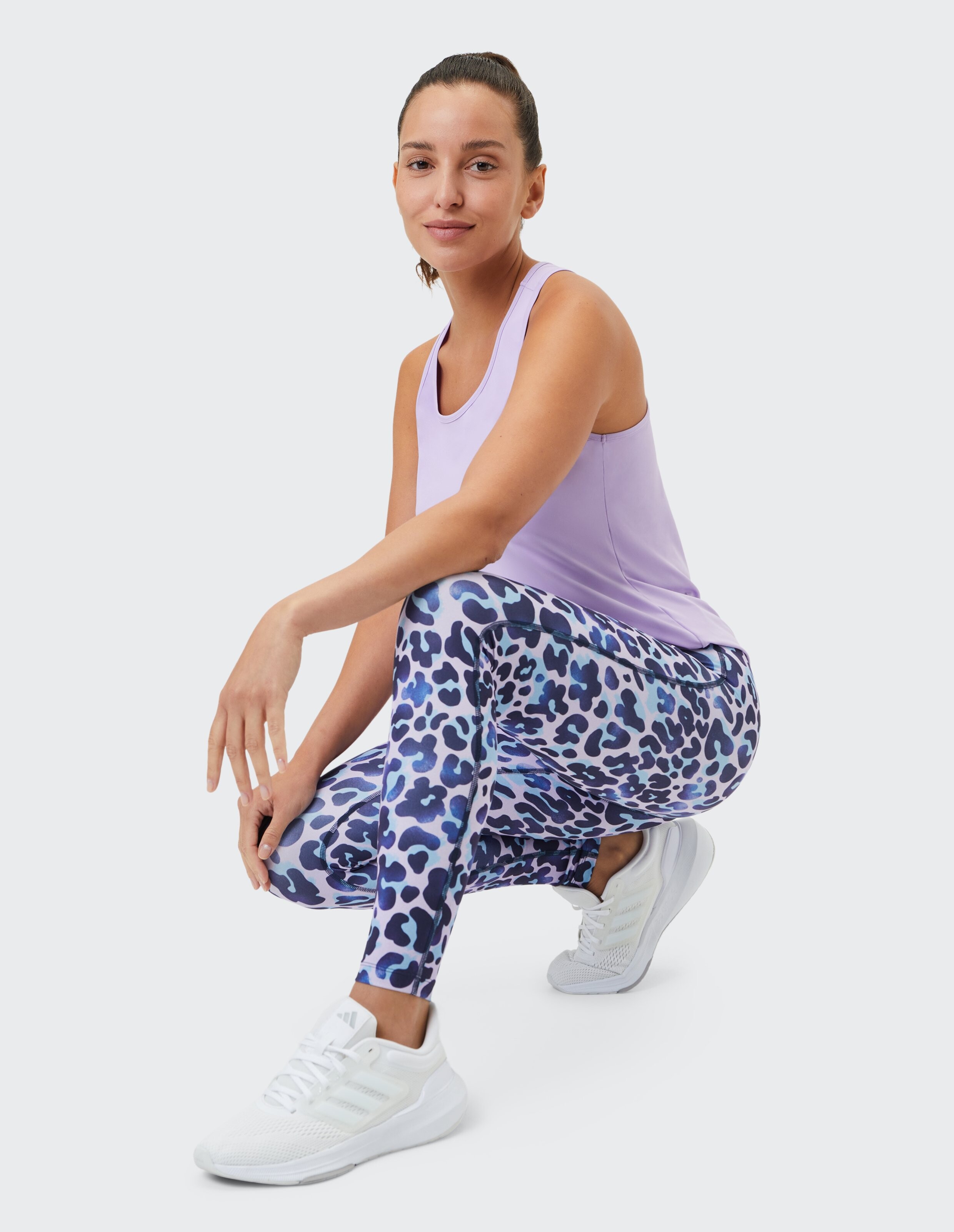 Frau in einem fliederfarbenen Tanktop und Leggings mit Leopardenmuster, gestylt für Freizeitkleidung.