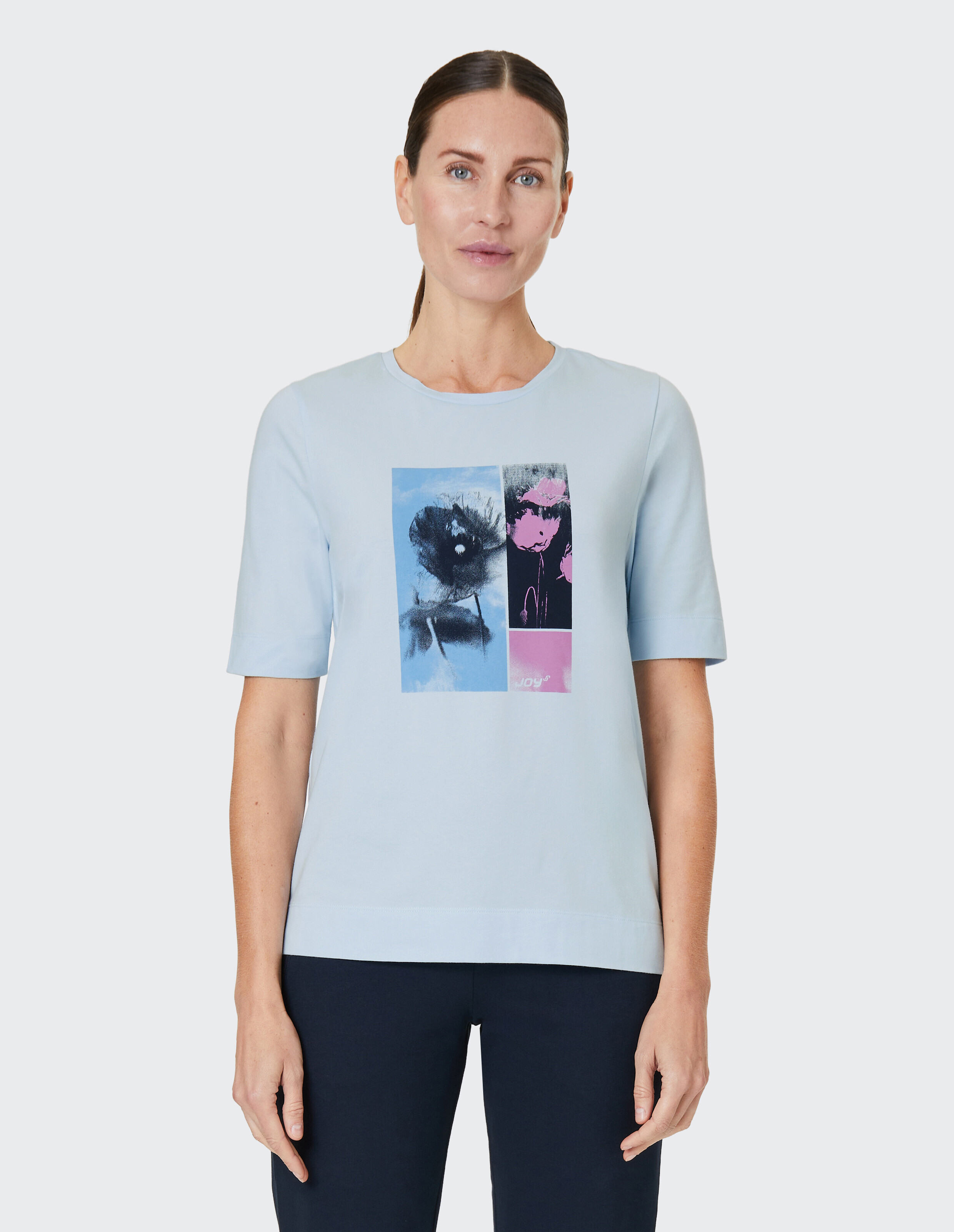 Hellblaues T-Shirt mit zweigeteiltem Kunstmotiv; links blaues Blumenbild, rechts rosa abstraction, darunter der Schriftzug \\\"Joy\\\""."