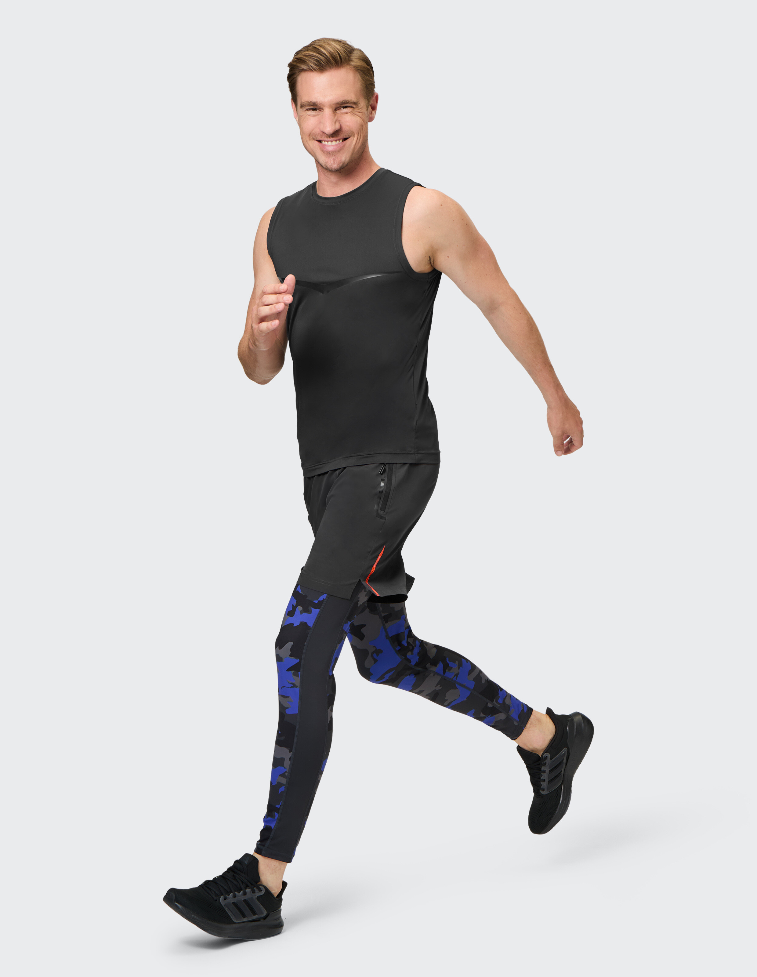 Mann joggt in einem ärmellosen schwarzen Top und blauen Camo-Leggings und präsentiert lässige Sportkleidung.