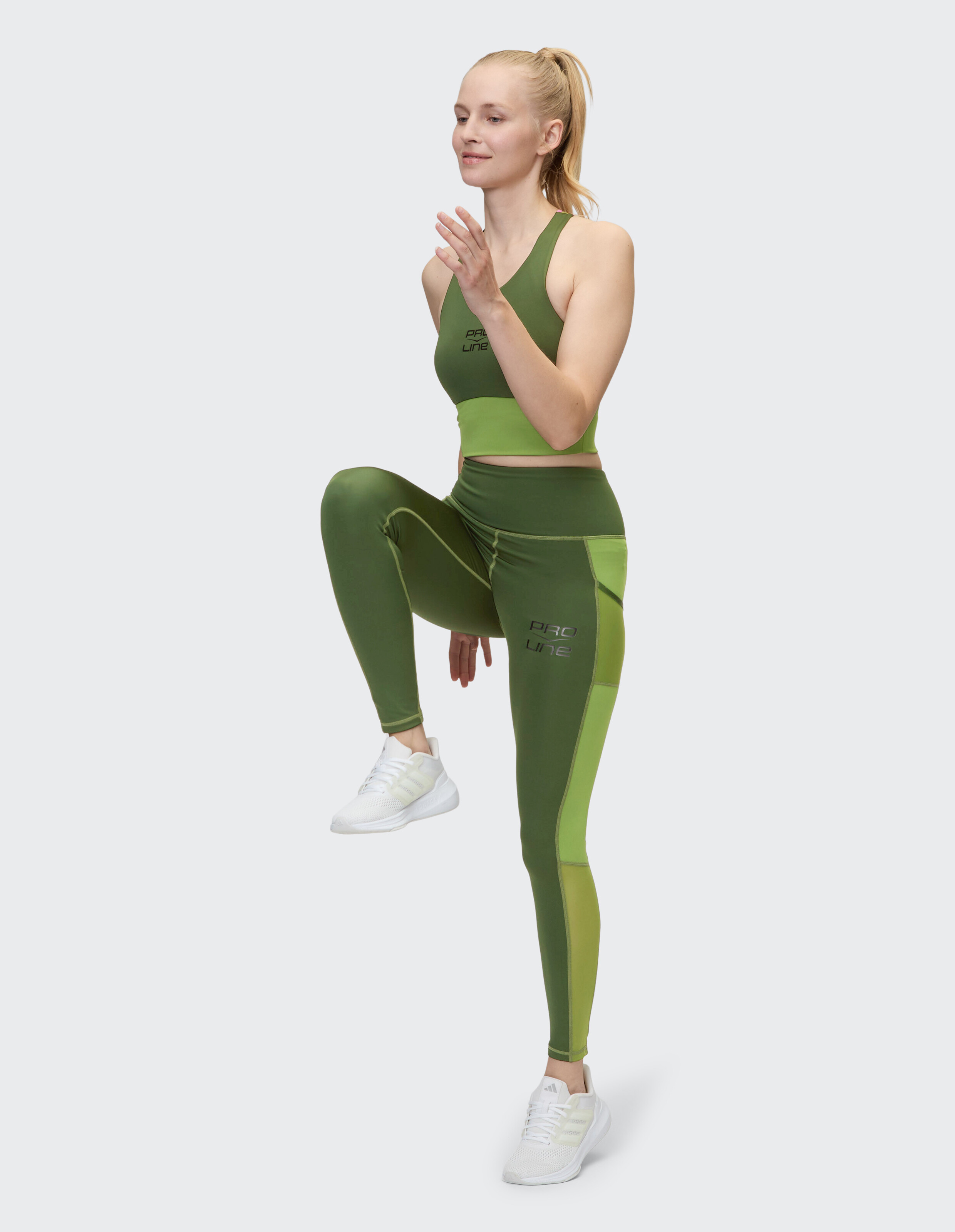 Model trägt grünen Sport-BH und Leggings, ideal für lässige Aktivkleidung.