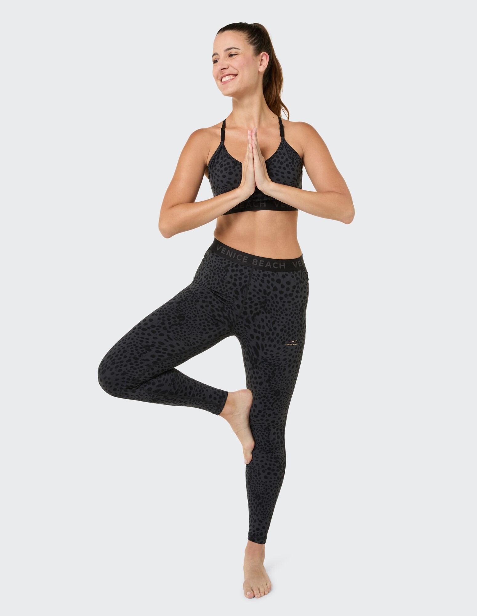 Frau im schwarzen Activewear-Set mit Leopardenmuster, perfekt für Yoga oder Freizeitkleidung.