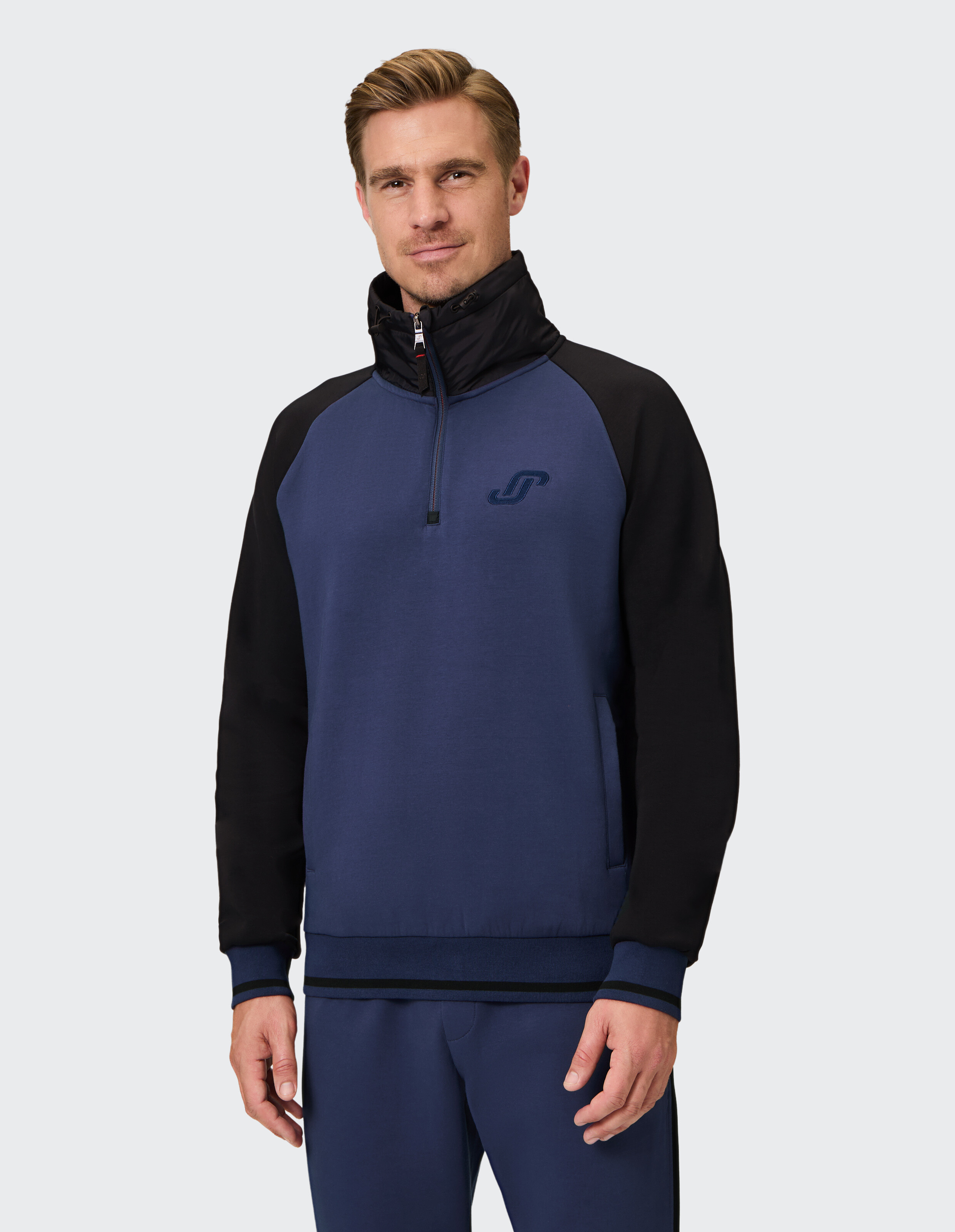 Mann trägt ein blau-schwarzes Sweatshirt mit Viertelreißverschluss für lässigen, gemütlichen Stil.