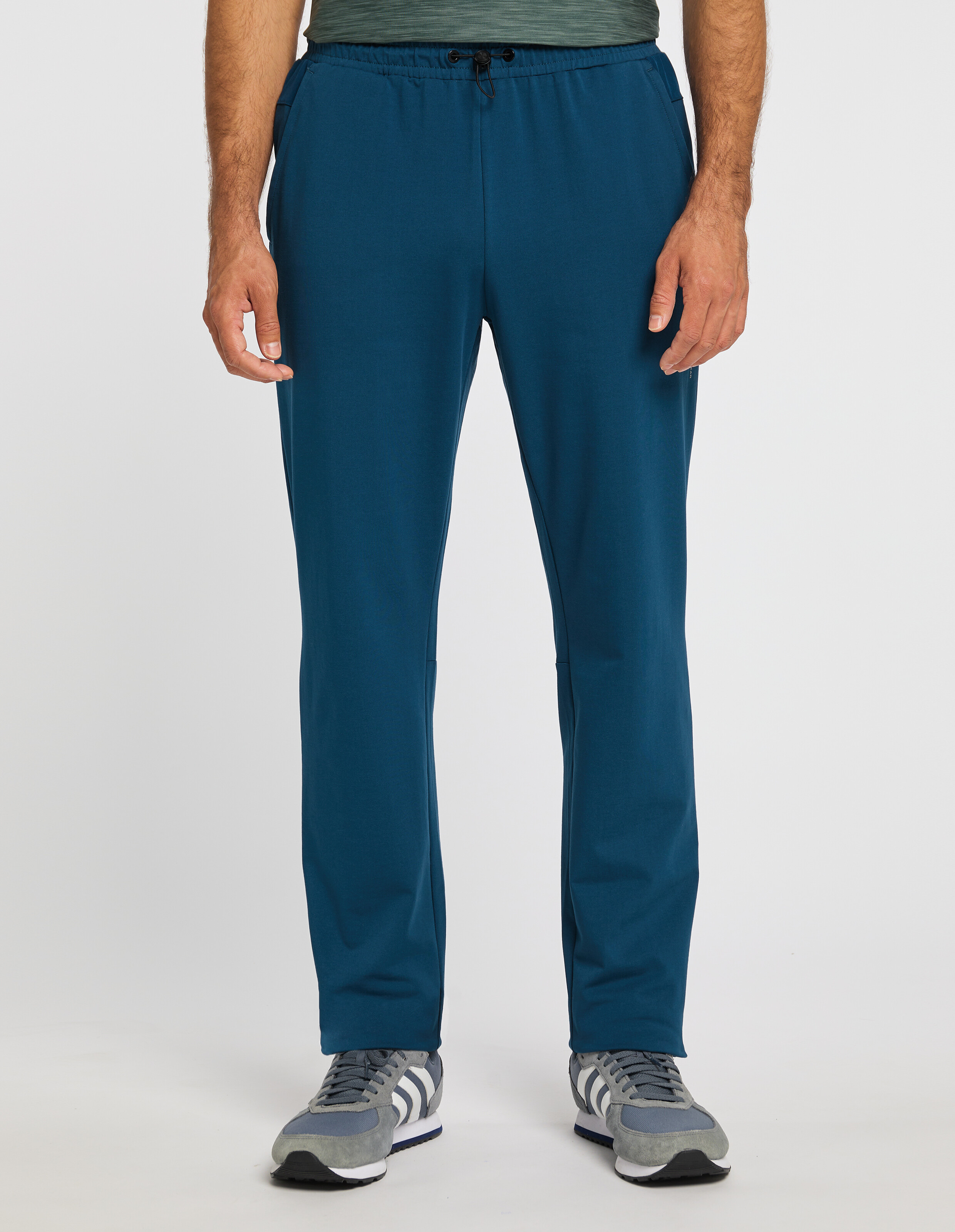 Person trägt eine blaue Jogginghose mit Kordelzug und graue Turnschuhe