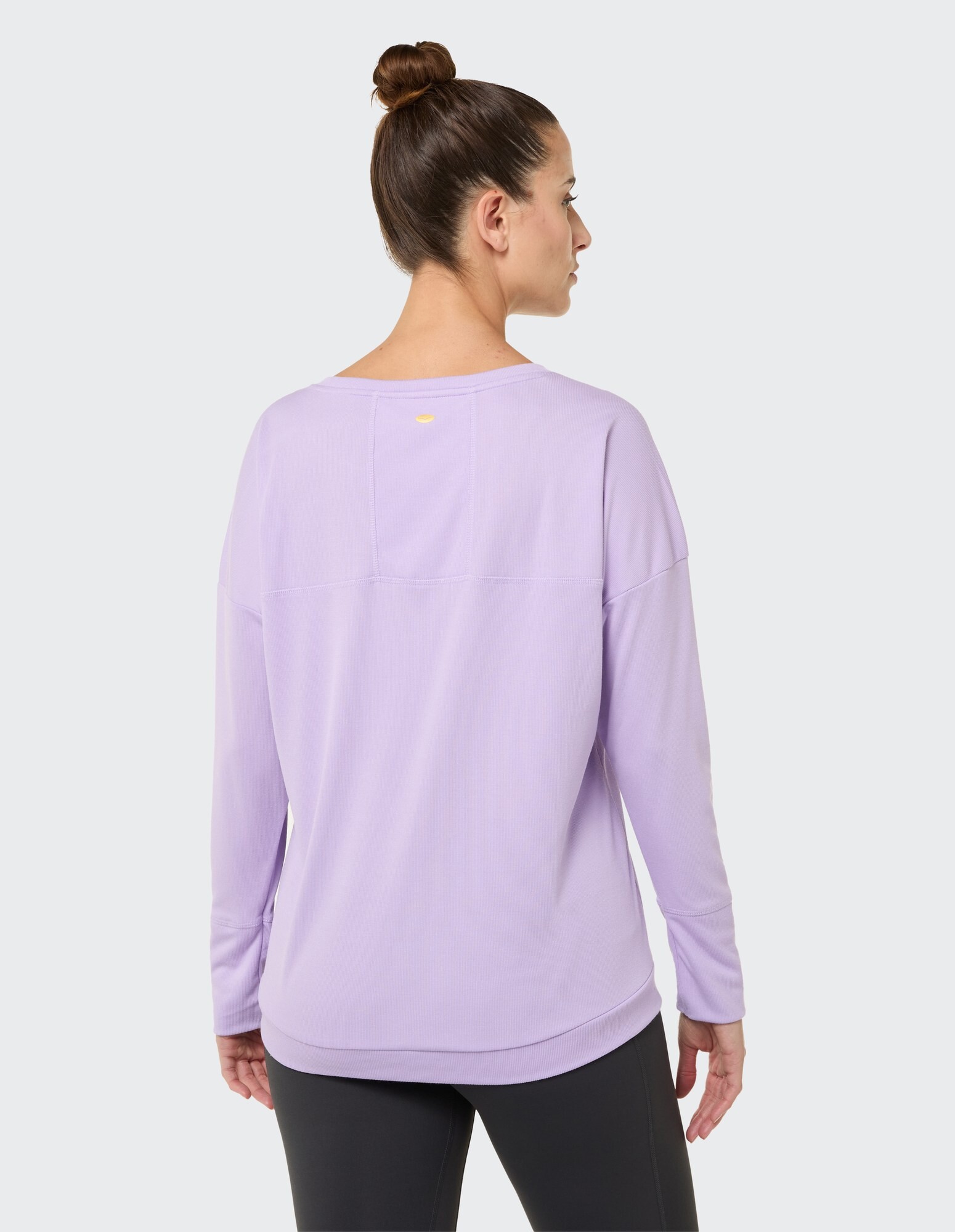 Rückansicht einer Frau, die ein lilafarbenes Langarmshirt mit lockerer Passform trägt.