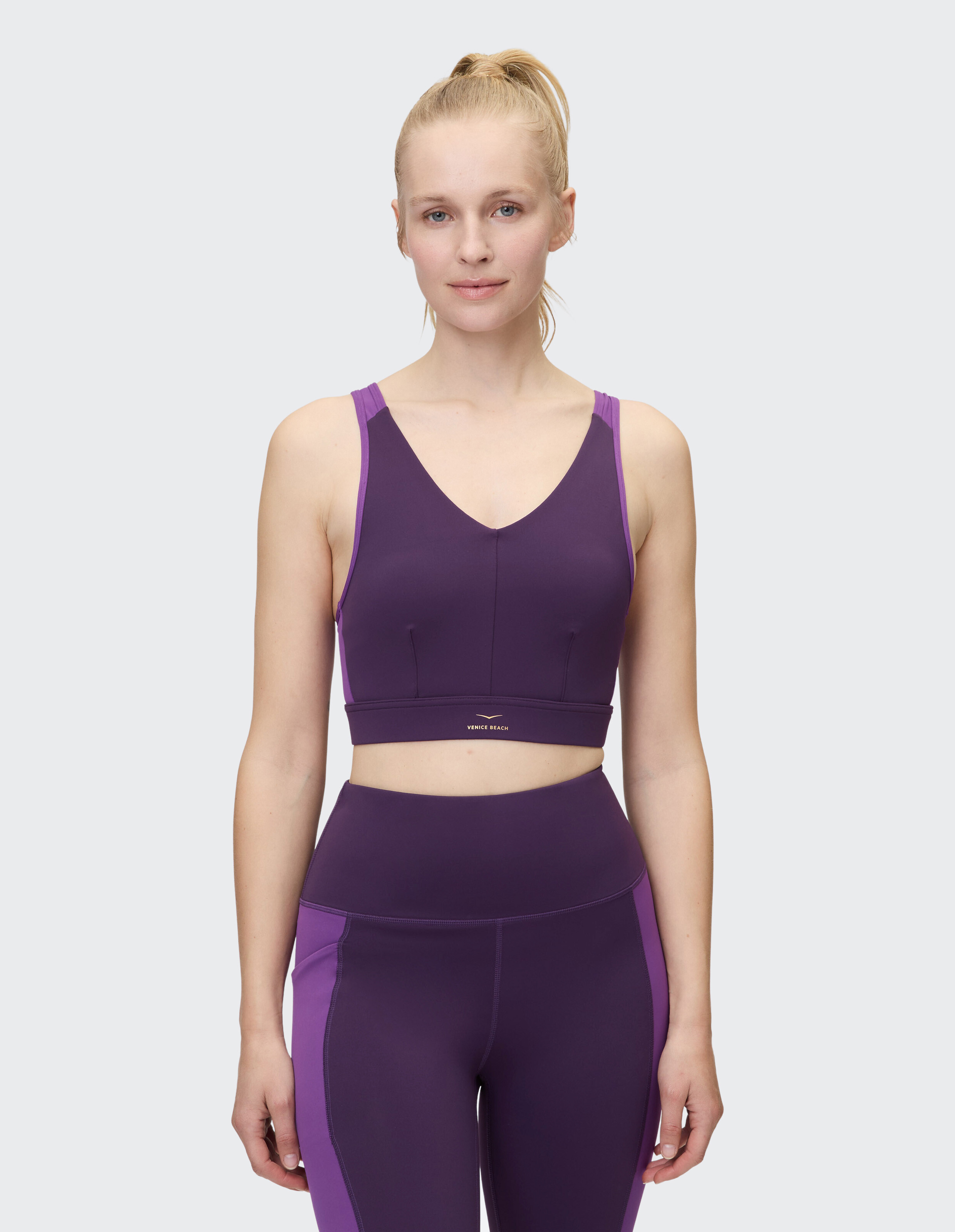 Das Model trägt einen lila Sport-BH und passende Leggings und präsentiert lässige Aktivkleidung.