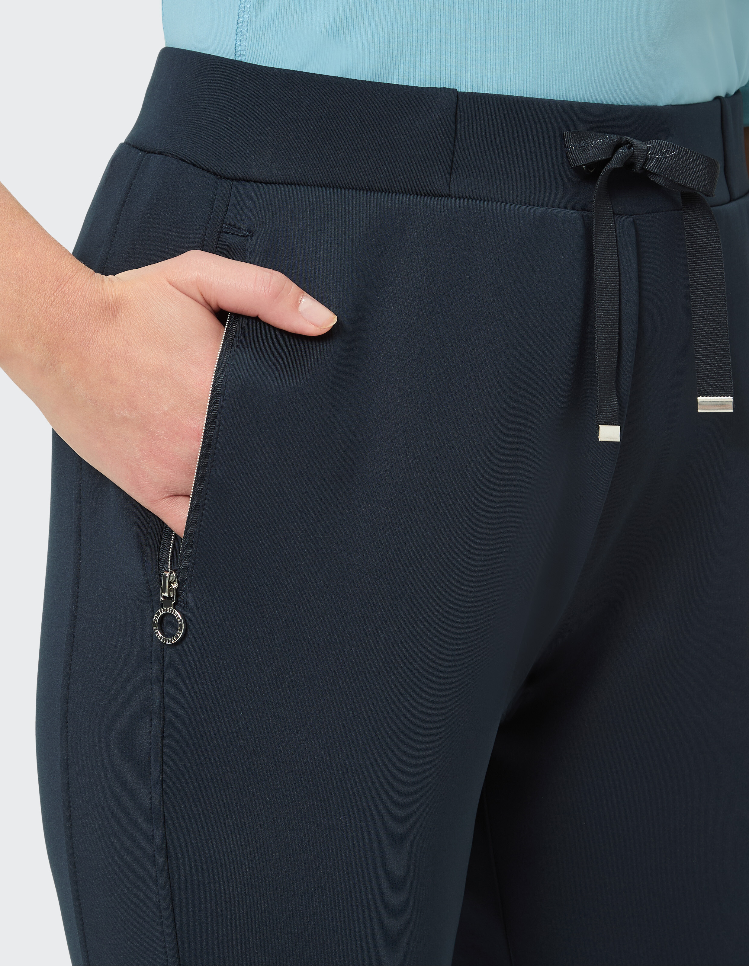 Nahaufnahme einer marineblauen Freizeithose mit Kordelzug und Reißverschlusstaschendetail.