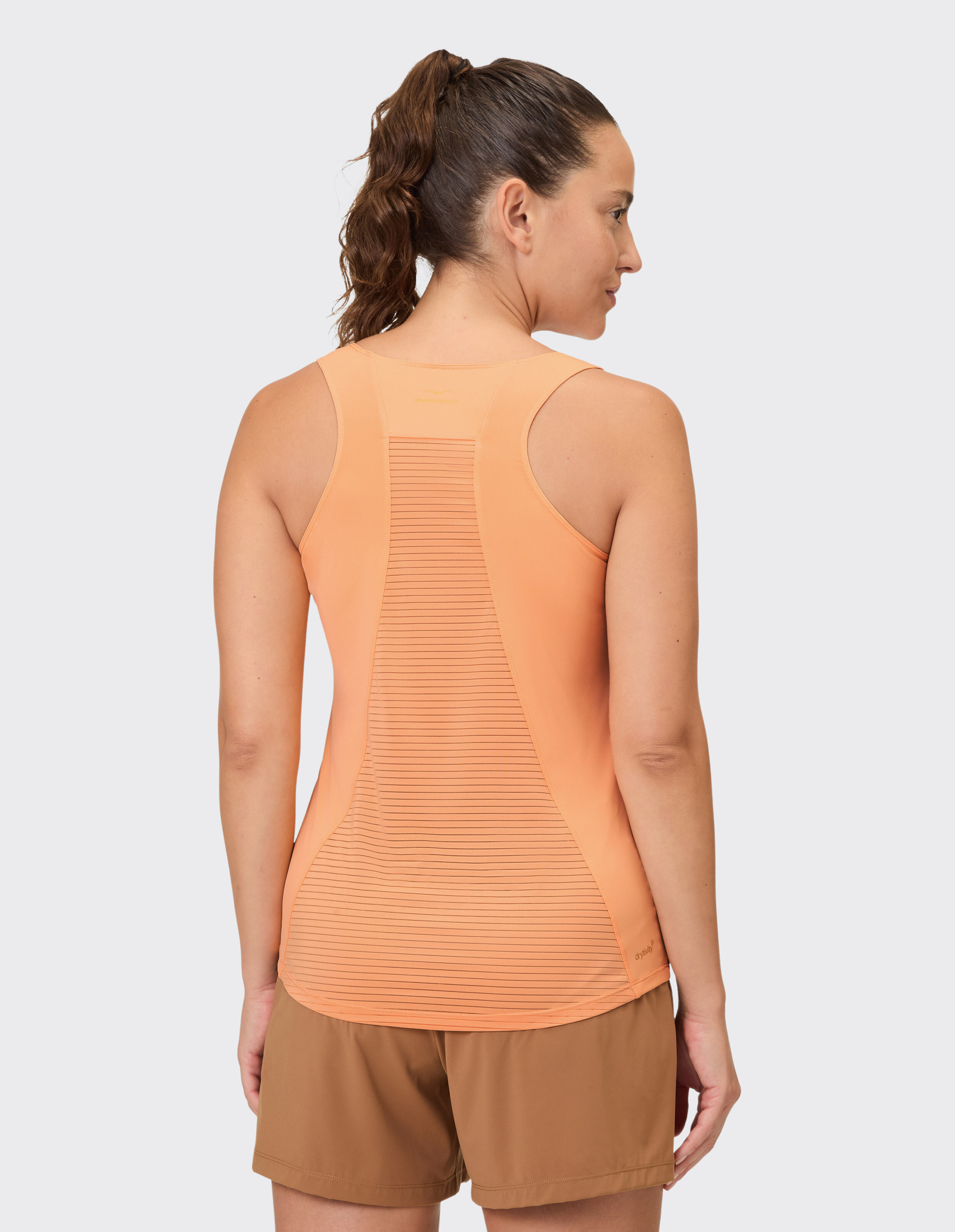 Frau trägt ein orangefarbenes Racerback-Tanktop mit Mesh-Einsätzen für lässige Aktivkleidung.