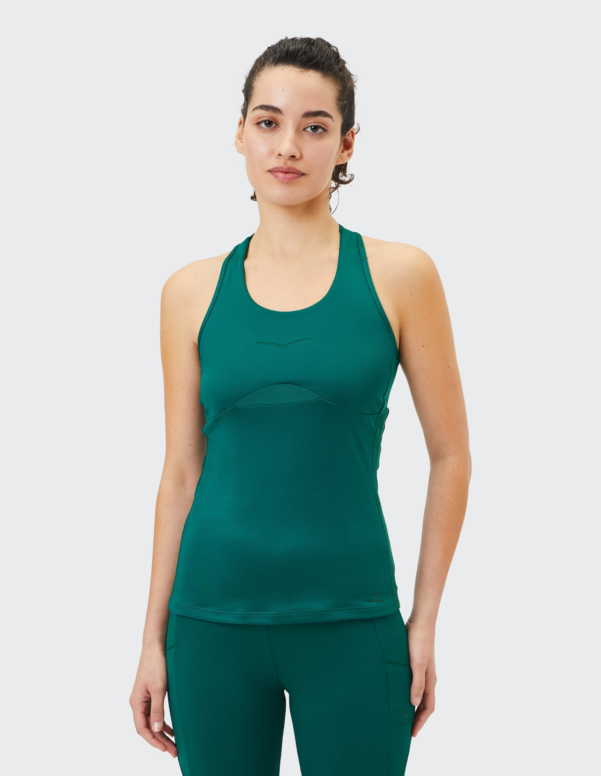 Das Model trägt ein grünes Sport-Tanktop, perfekt für lässiges Training oder zum Faulenzen.