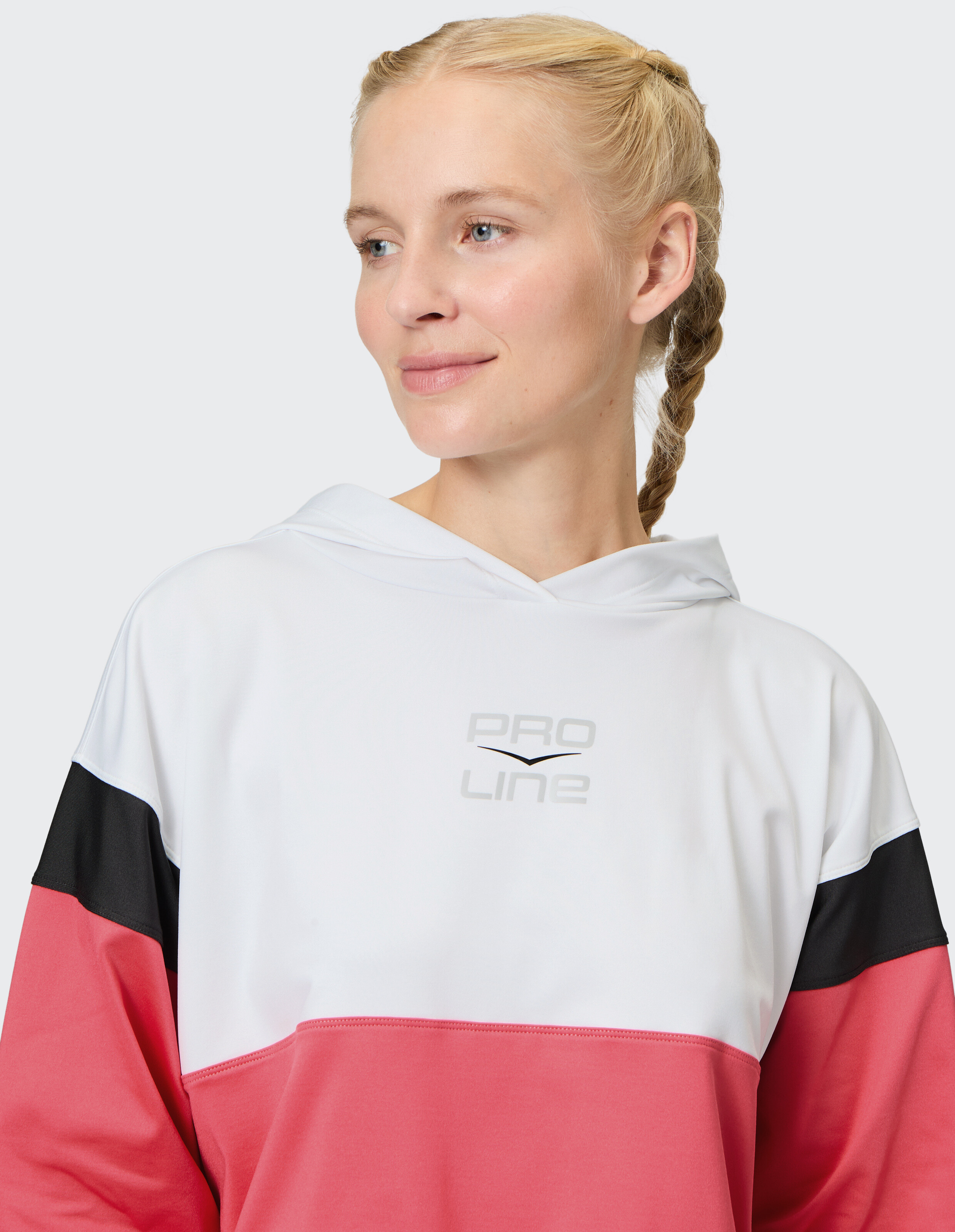 Frau trägt einen farbblockierten Kapuzenpullover in Rosa, Weiß und Schwarz, ideal für Freizeitkleidung.