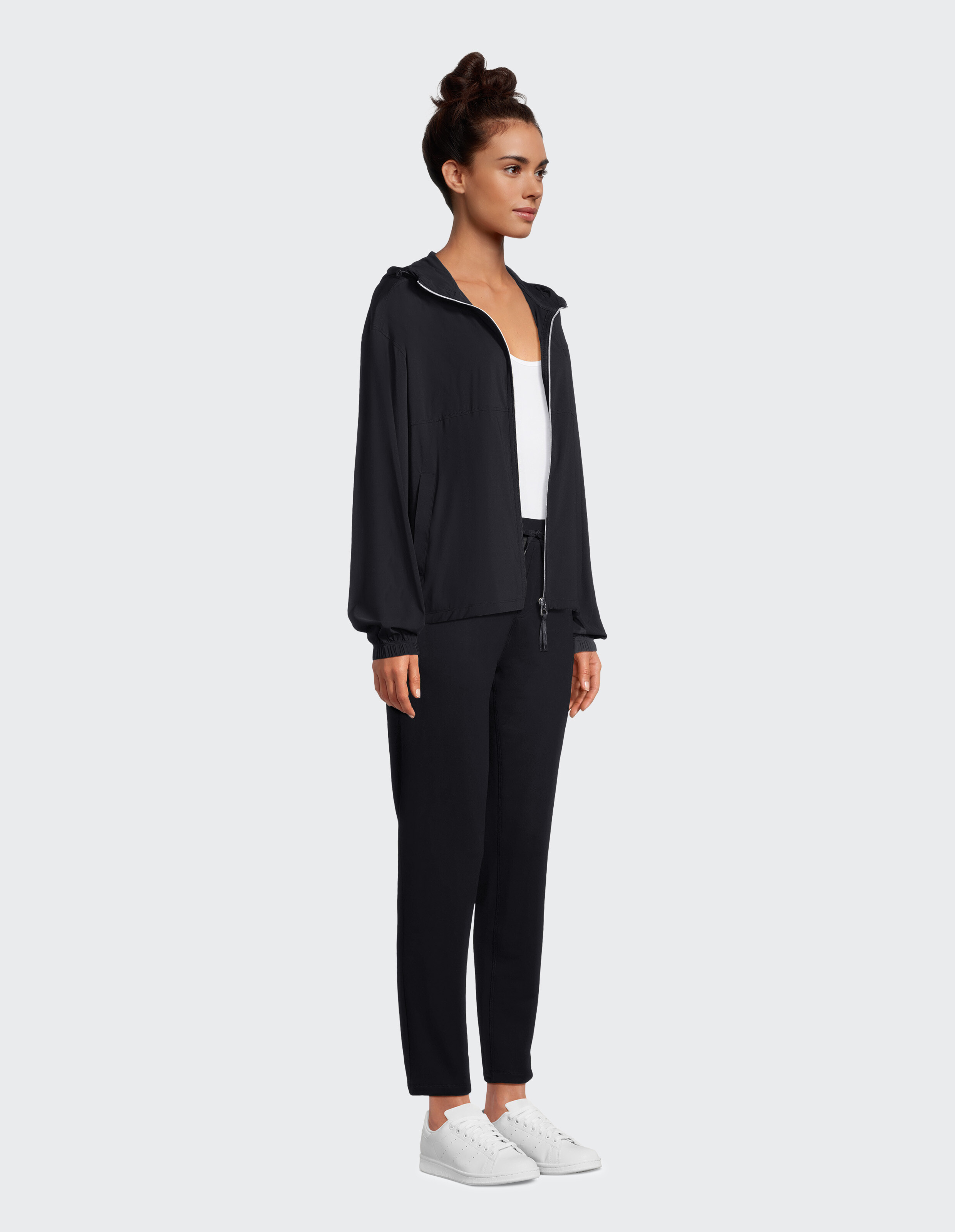 Frau in schwarzer Jacke und Hose mit Reißverschluss, lässig gestylt.