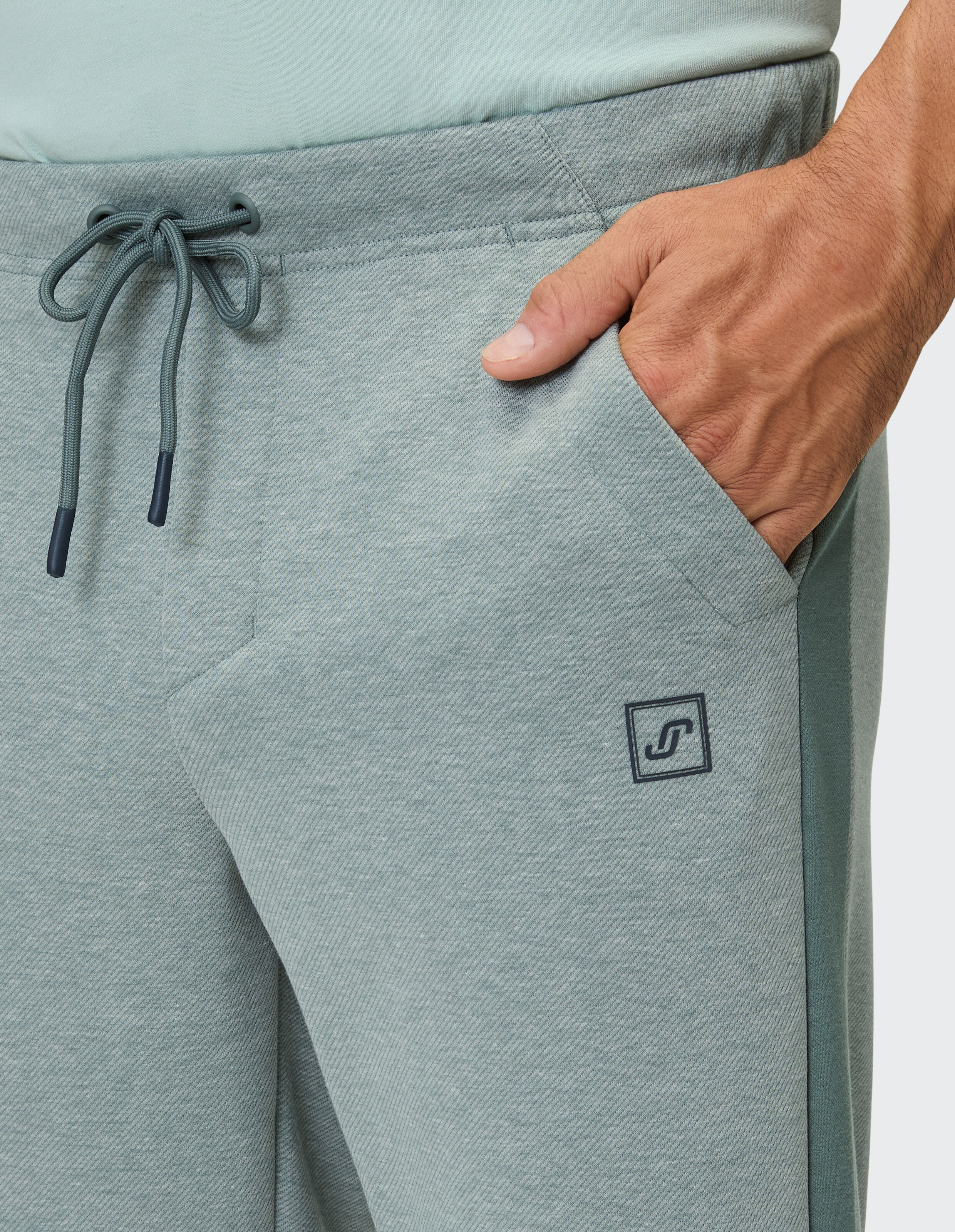 Nahaufnahme einer hellgrauen Jogginghose mit Kordelzug und Seitentaschen.