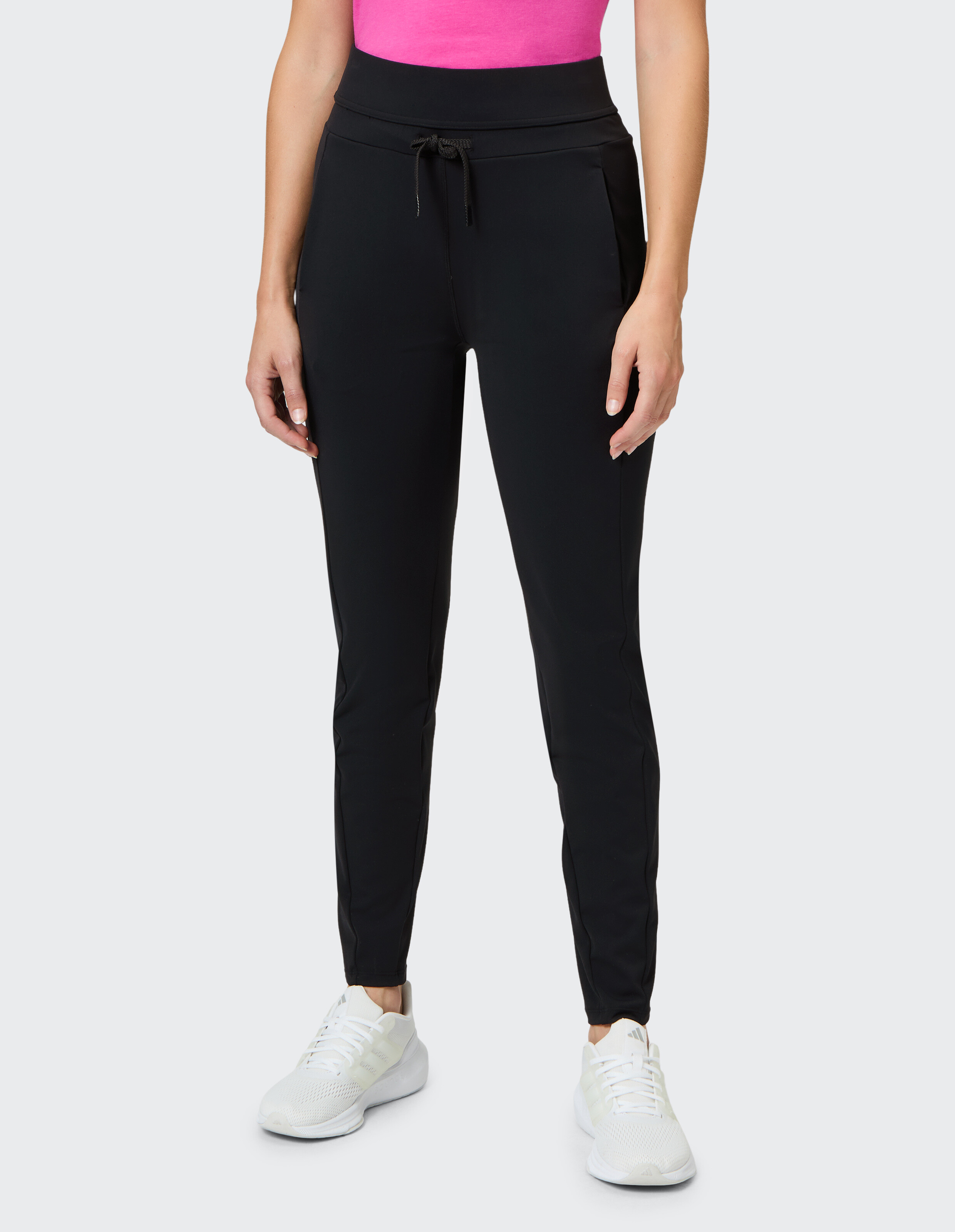 Schwarze Jogginghose mit hohem Bund und Kordelzug, gepaart mit weißen Sneakers.