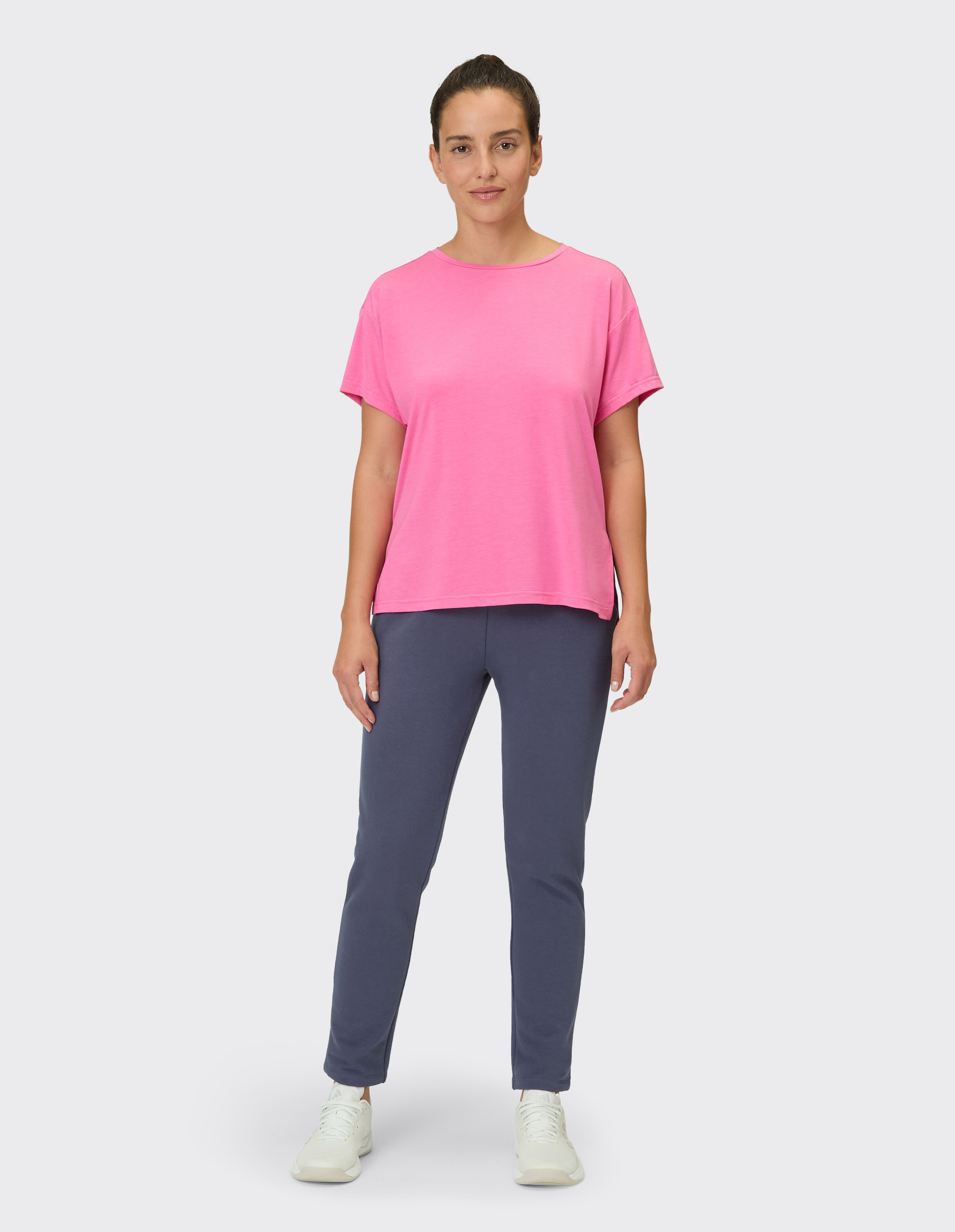 Frau trägt ein leuchtend rosafarbenes Freizeit-T-Shirt und eine dunkelblaue Hose für einen bequemen Lounge-Look.