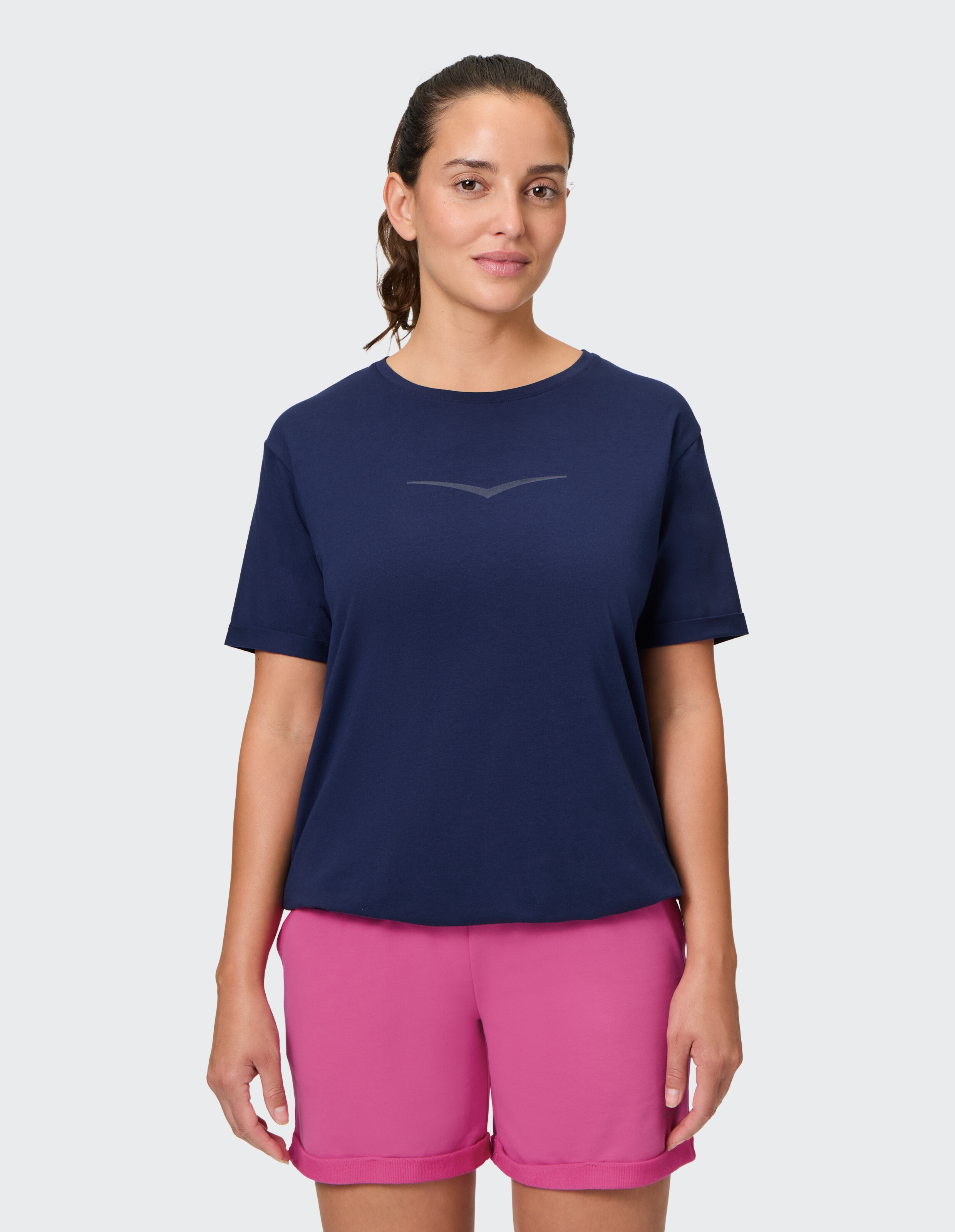 Frau trägt ein dunkelblaues Freizeit-T-Shirt und rosa Shorts für einen bequemen Lounge-Look.
