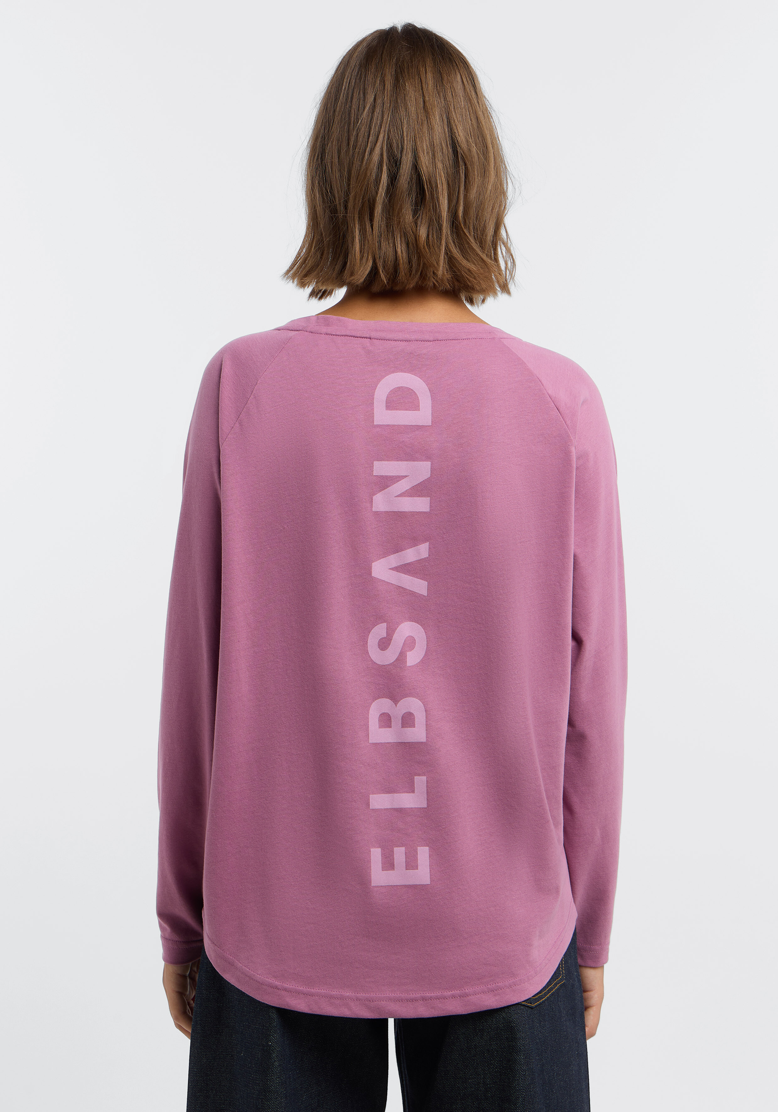 Frau trägt ein altrosa ELBSAND-Langarmshirt mit Logo-Aufdruck auf der Rückseite.