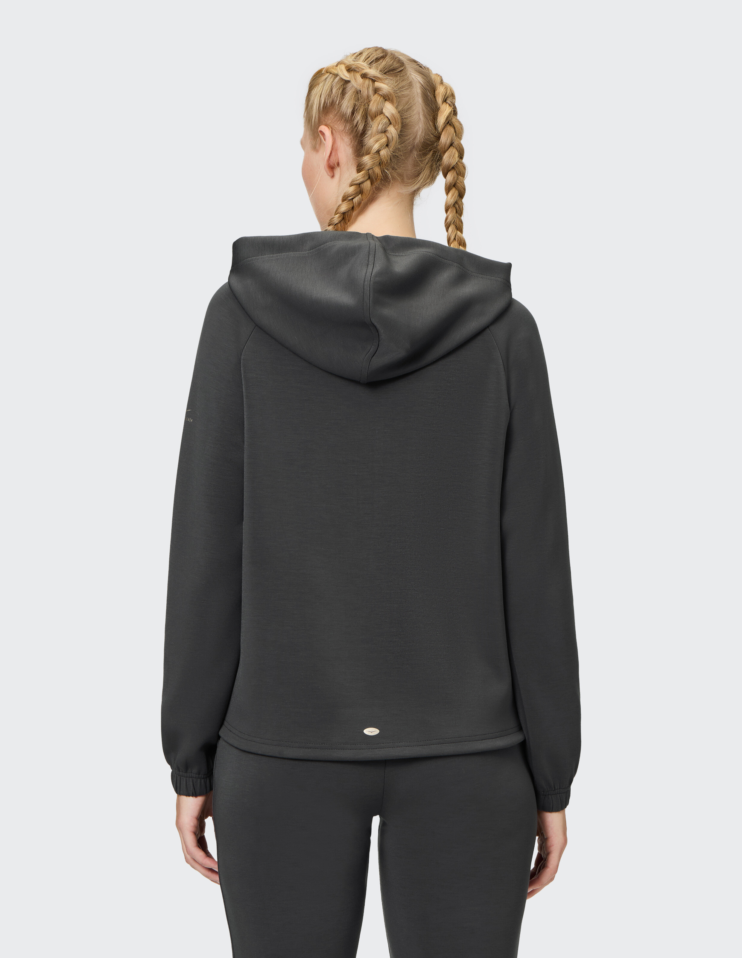 Frau trägt einen kuscheligen dunkelgrauen ELBSAND-Hoodie zum entspannten Faulenzen und Reisen.