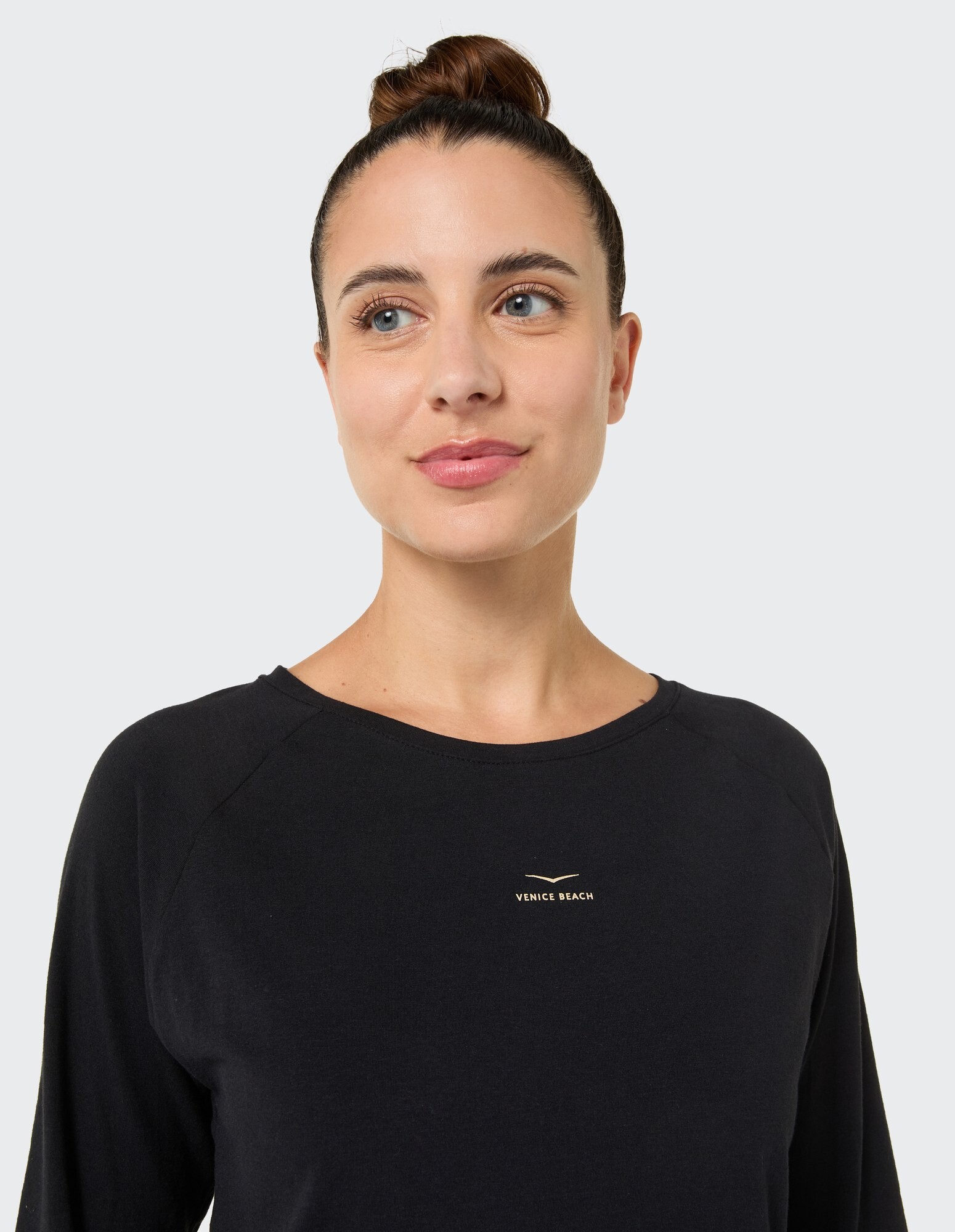 Nahaufnahme einer Frau in einem schwarzen Langarmshirt mit „Venice Beach“-Logo.