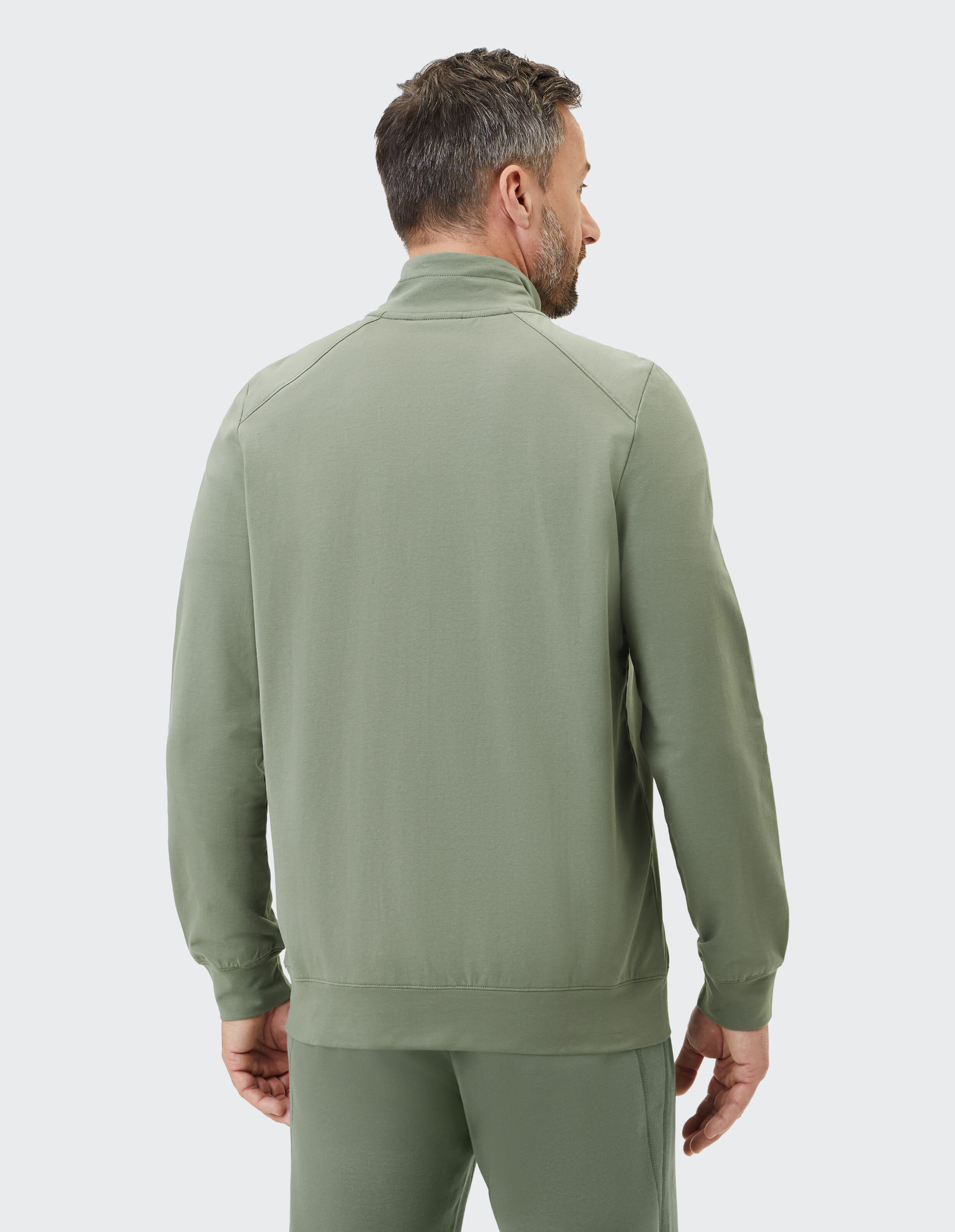Grüne Unisex-Freizeitjacke mit durchgehendem Reißverschluss, zwei Reißverschlusstaschen und hohem Kragen aus leichtem Material.