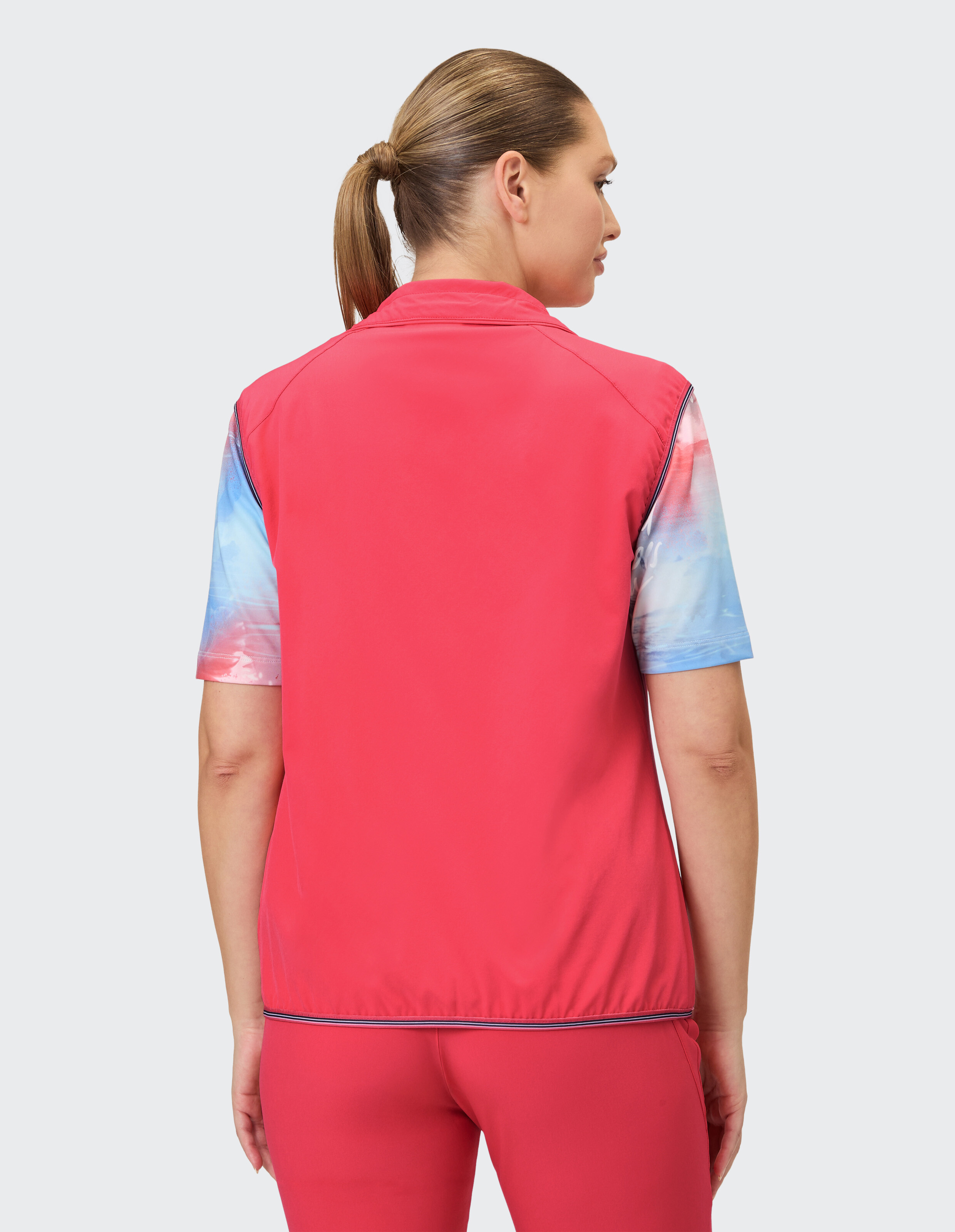 Rückansicht einer Frau in einer rosa Weste mit bunten Ärmeln, ideal für Freizeitkleidung.