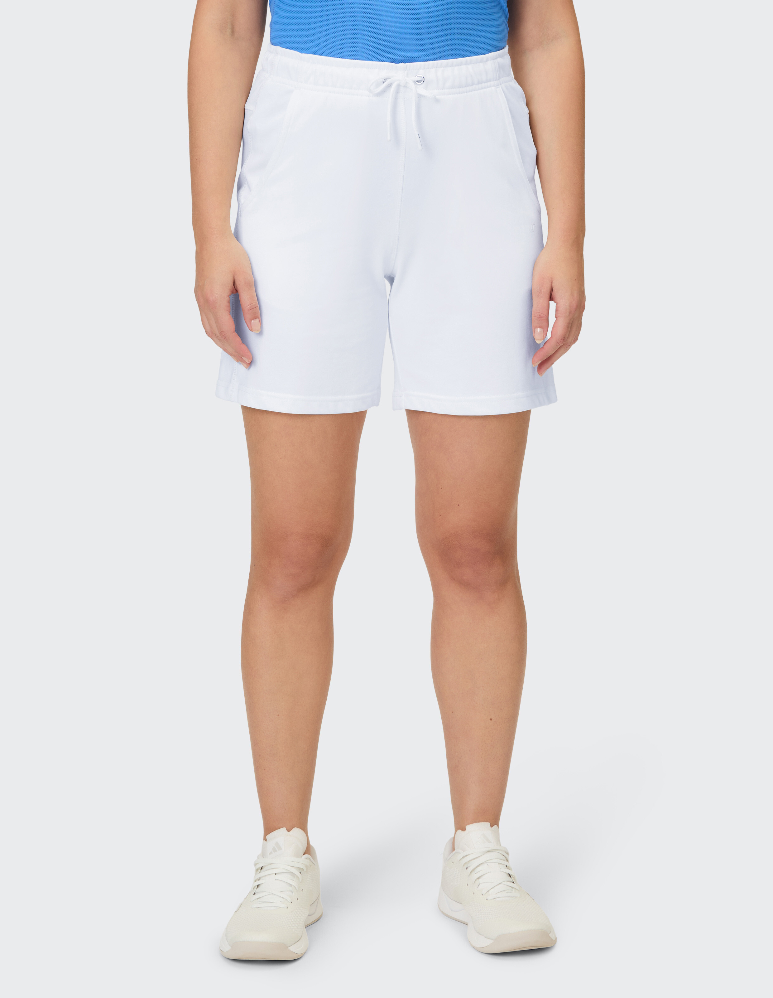 Eine Frau trägt weiße Trainingsshorts mit einem Kordelzugbund und passende Laufschuhe.