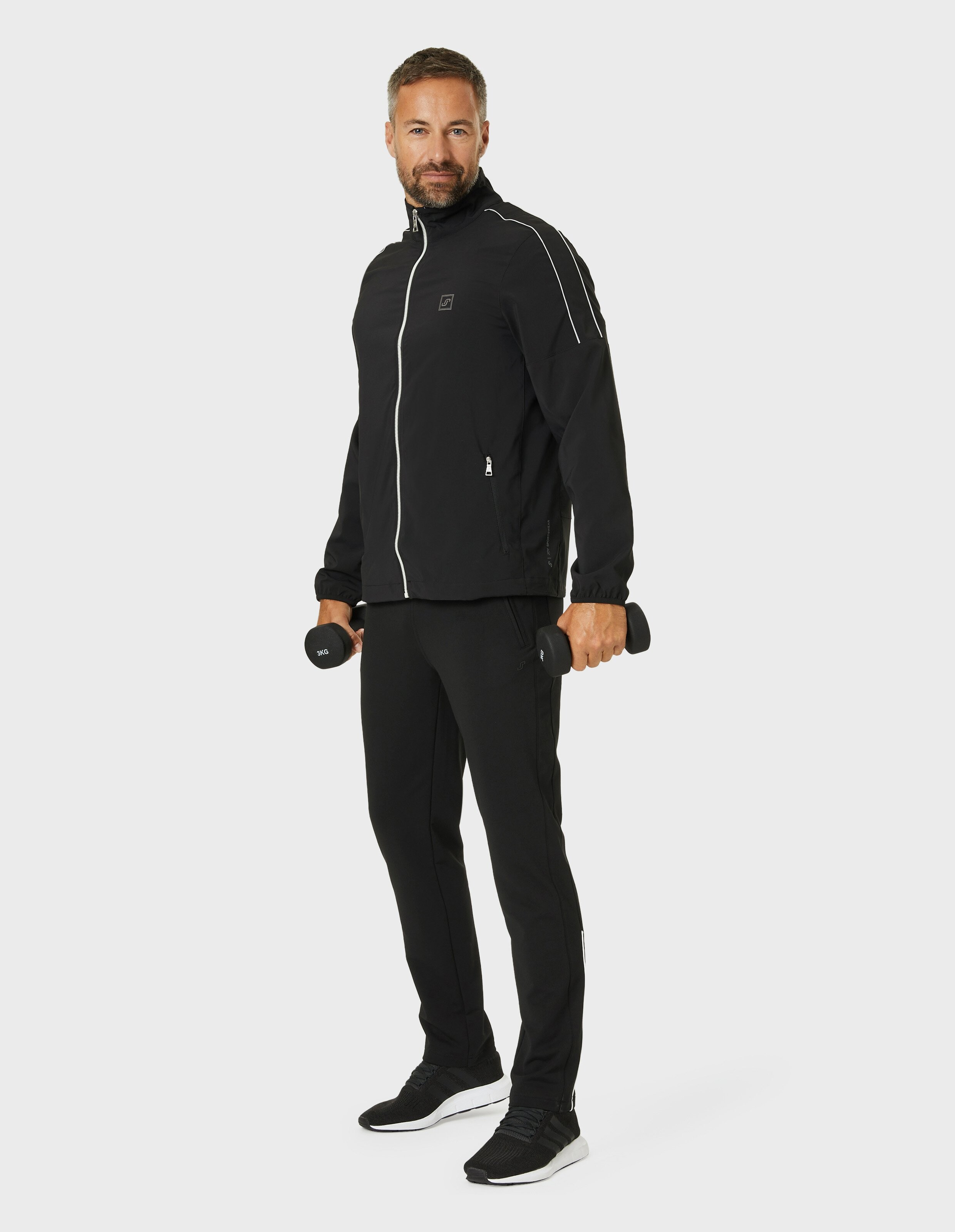 Eine schwarze Jacke mit weißem Reißverschluss und Paspeln, hohem Kragen und zwei Taschen mit Reißverschluss auf der Vorderseite.