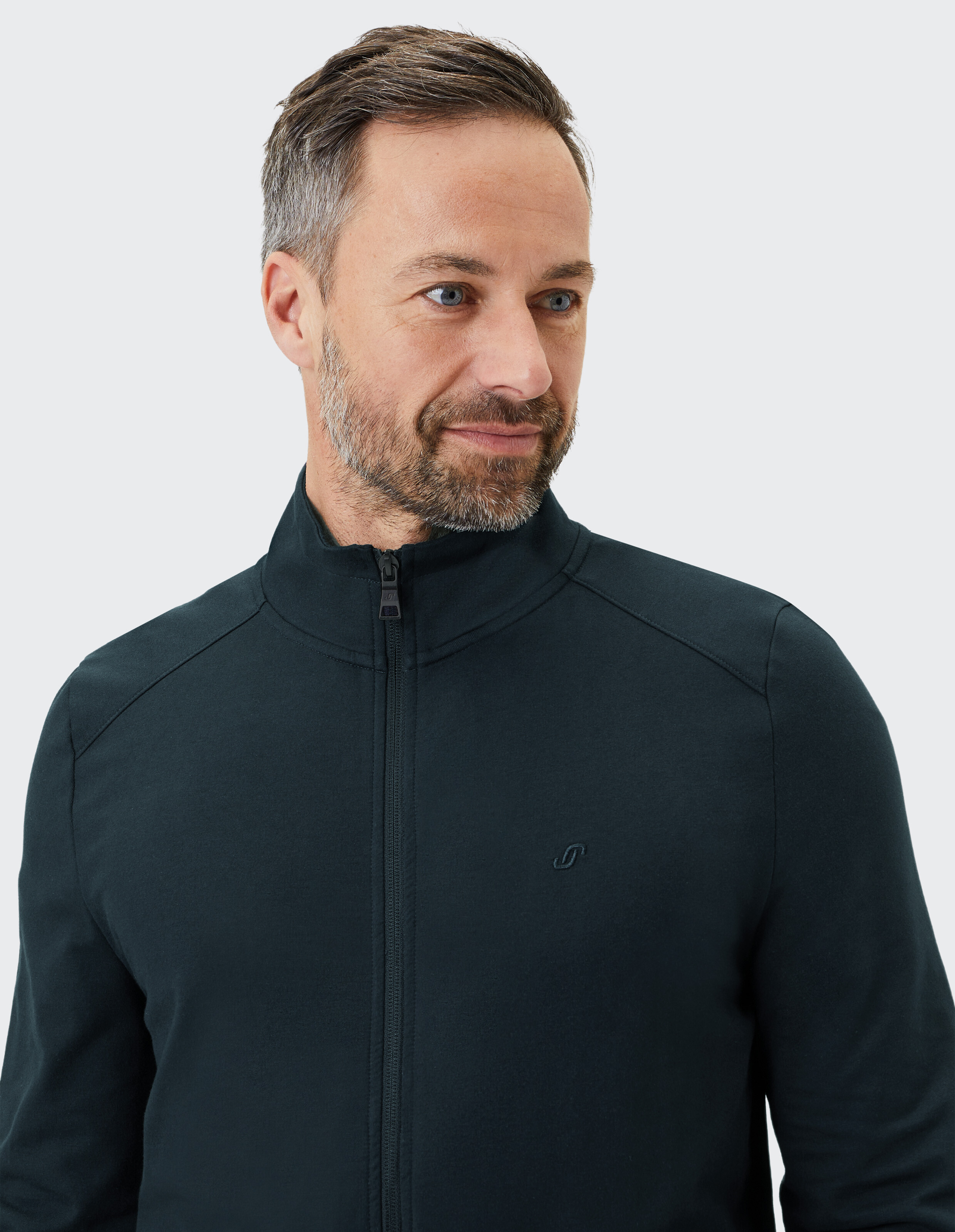 Mann trägt eine dunkelgrüne ELBSAND-Reißverschlussjacke für lässigen, bequemen Stil.