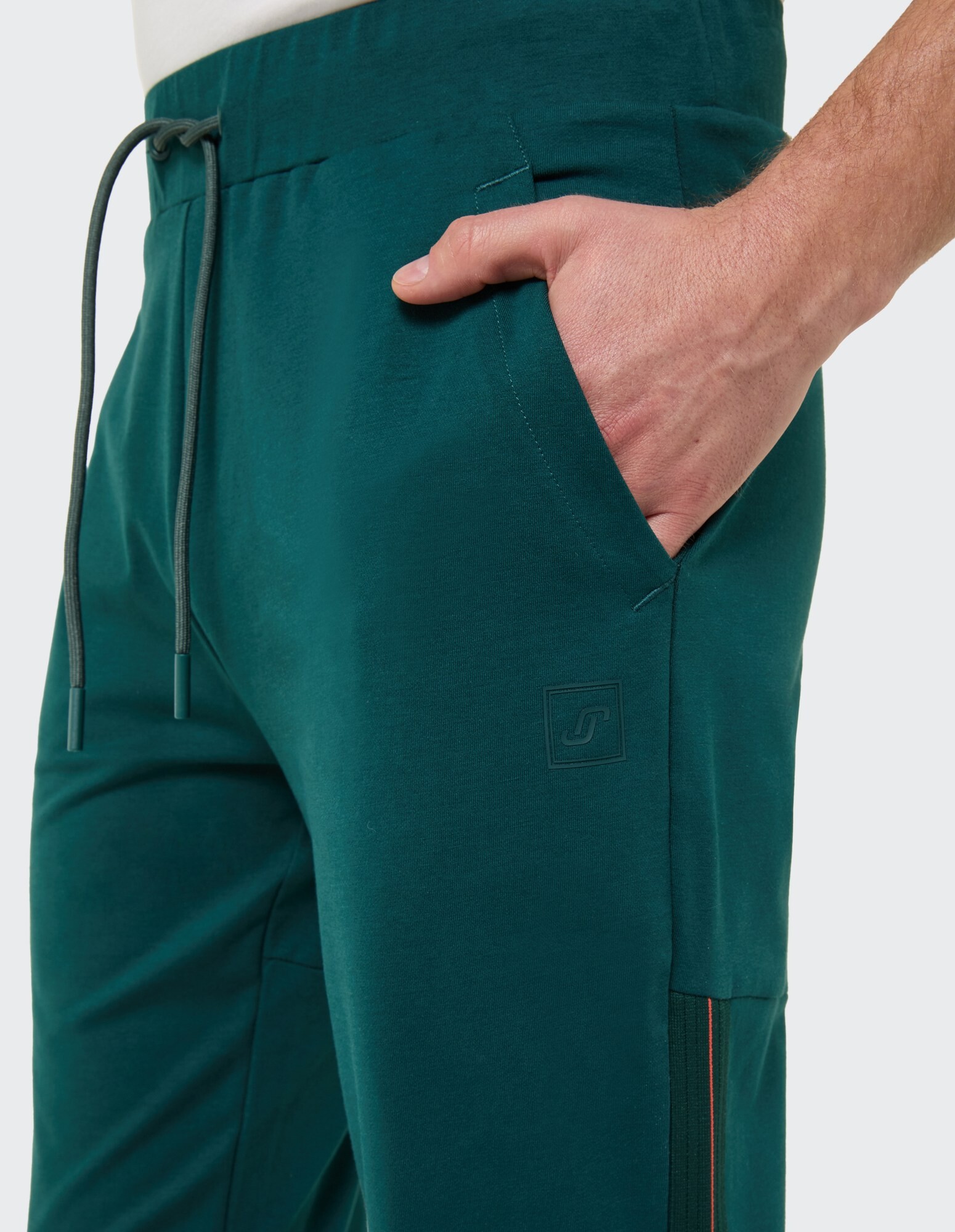 Nahaufnahme einer blaugrünen Freizeithose mit Seitentaschen und Kordelzug in der Taille.