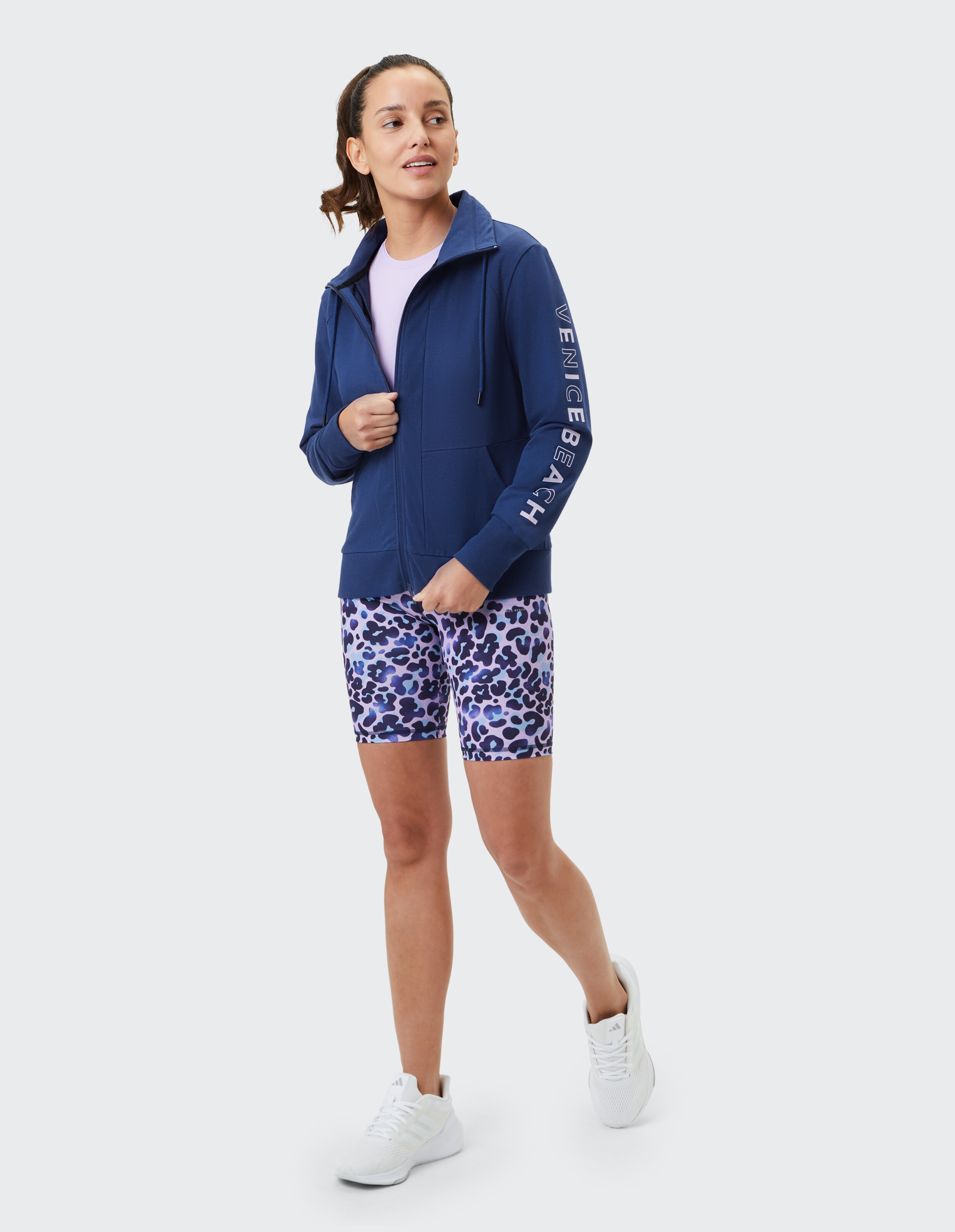 Frau trägt eine blaue Reißverschlussjacke von Venice Beach Avery und gemusterte Shorts.