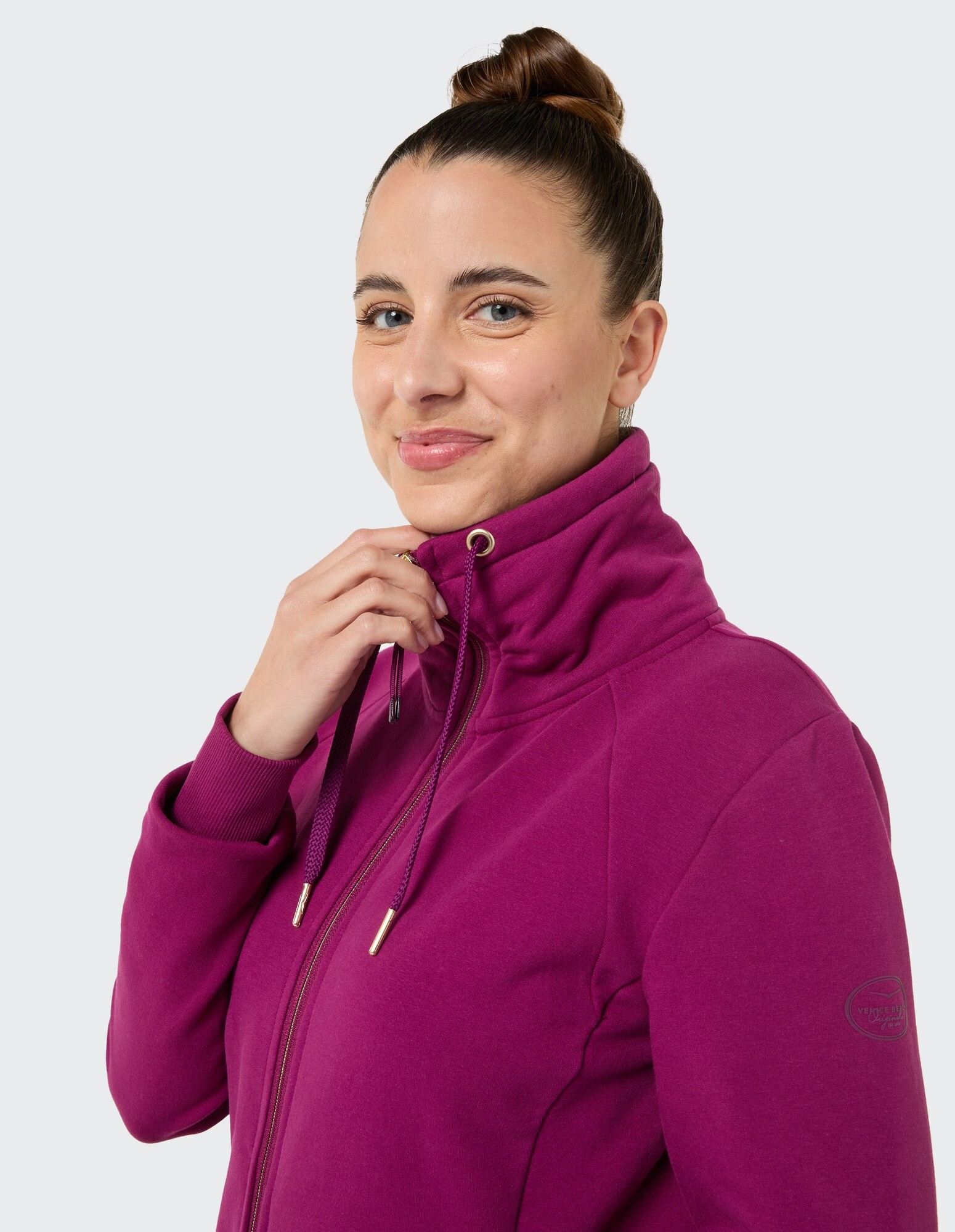 Nahaufnahme einer Frau in einem lila Kapuzenpullover mit Reißverschluss, die einen gemütlichen, lässigen Stil zeigt.
