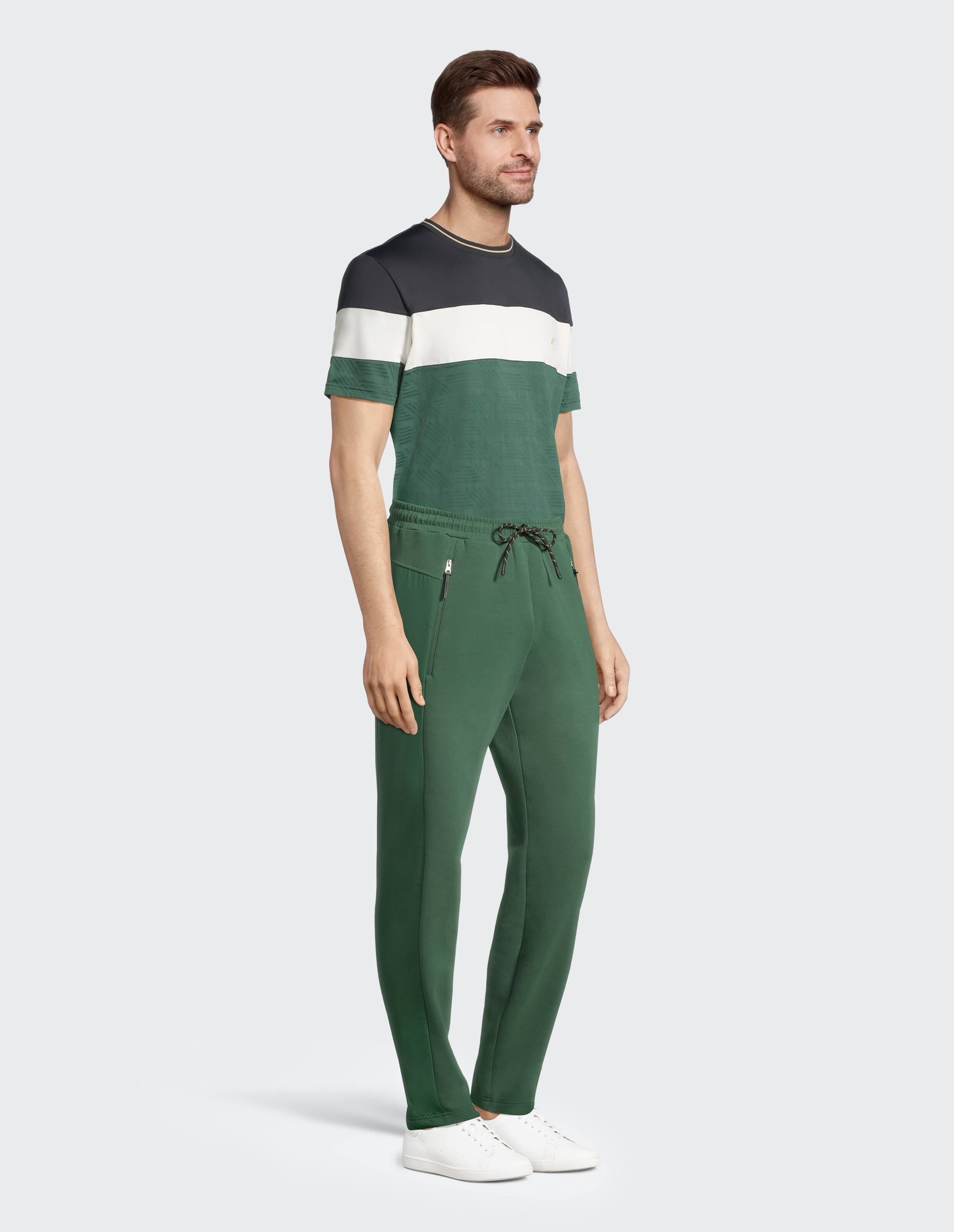 Mann trägt ein stilvolles T-Shirt in Colour-Block-Optik und grüne Jogginghosen, perfekt für Freizeitausflüge oder zum Faulenzen.