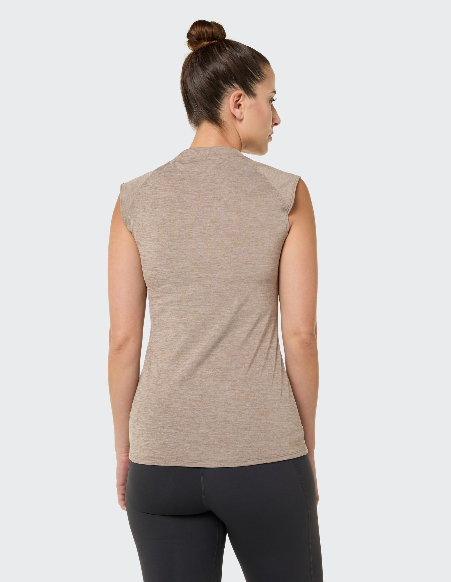 Rückansicht einer Frau, die ein beiges ärmelloses Top und schwarze Leggings trägt.