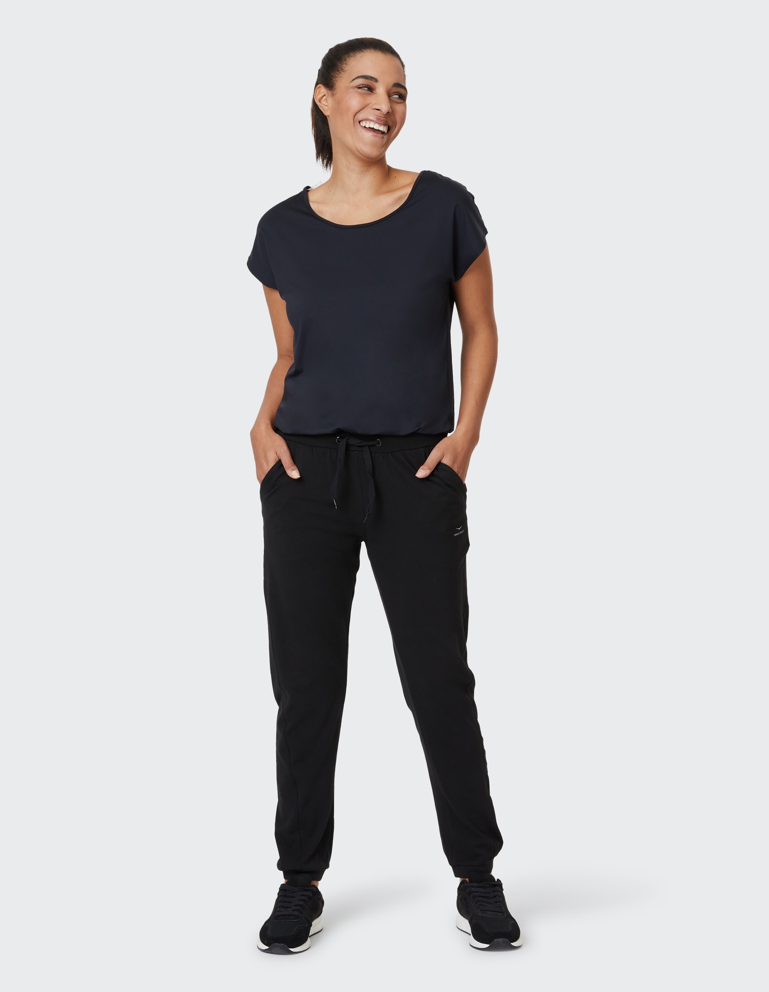 Frau trägt ein schwarzes Freizeit-T-Shirt und bequeme Jogginghosen für einen gemütlichen Lounge-Look.