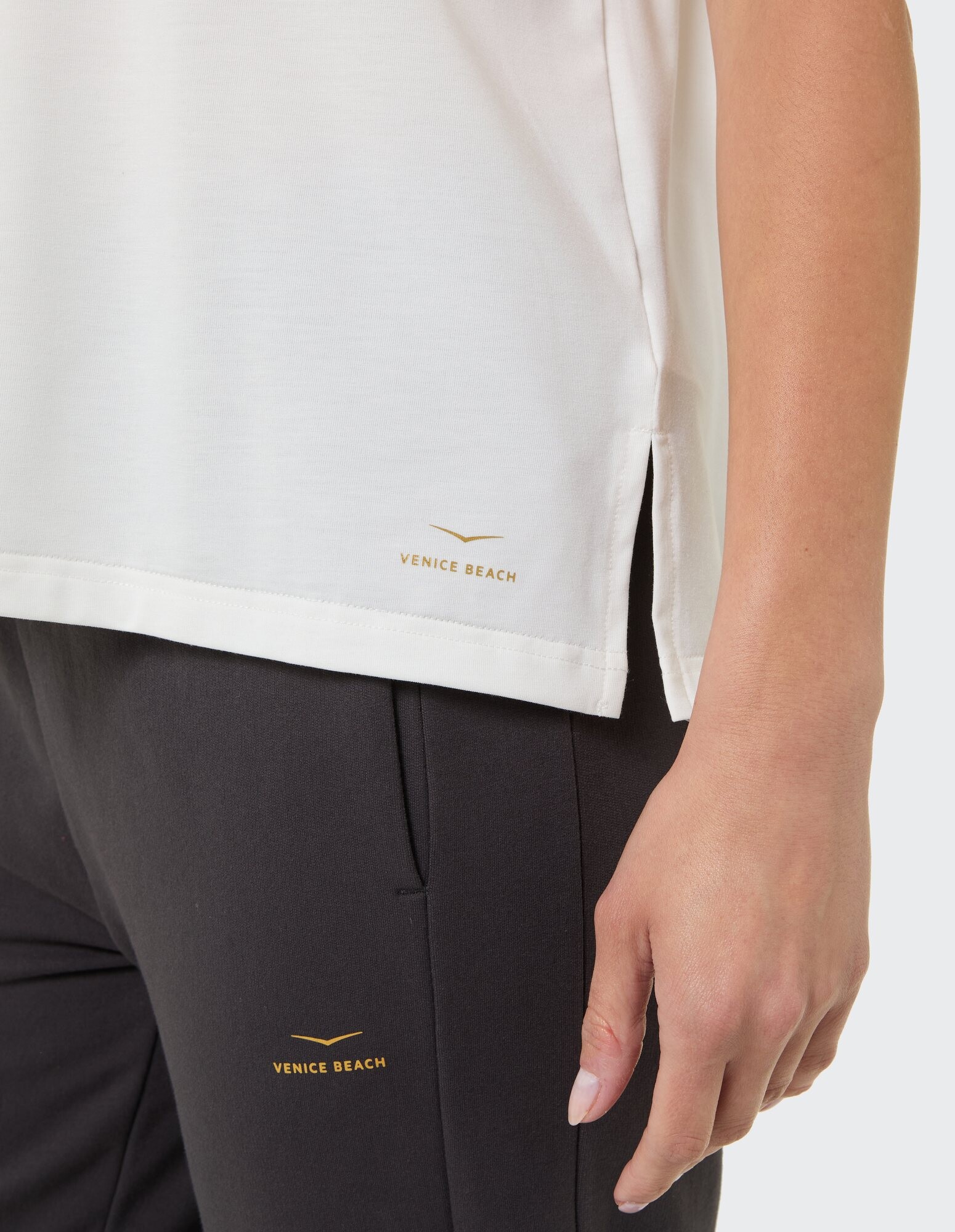 Nahaufnahme eines weißen Oberteils und einer schwarzen Hose mit dem Logo von Venice Beach.