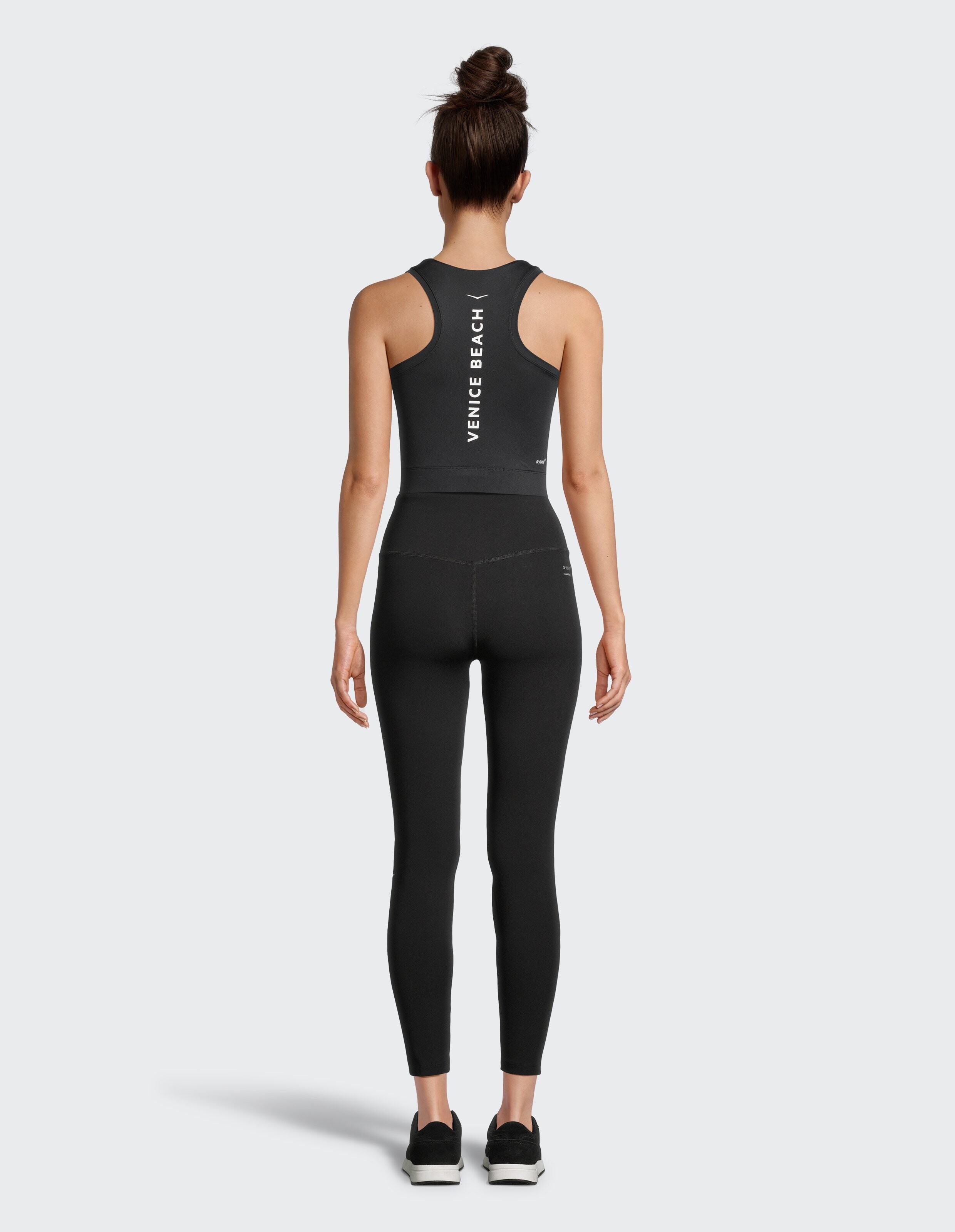 Frau trägt ein schwarzes Racerback-Tanktop von Venice Beach und passende Leggings.